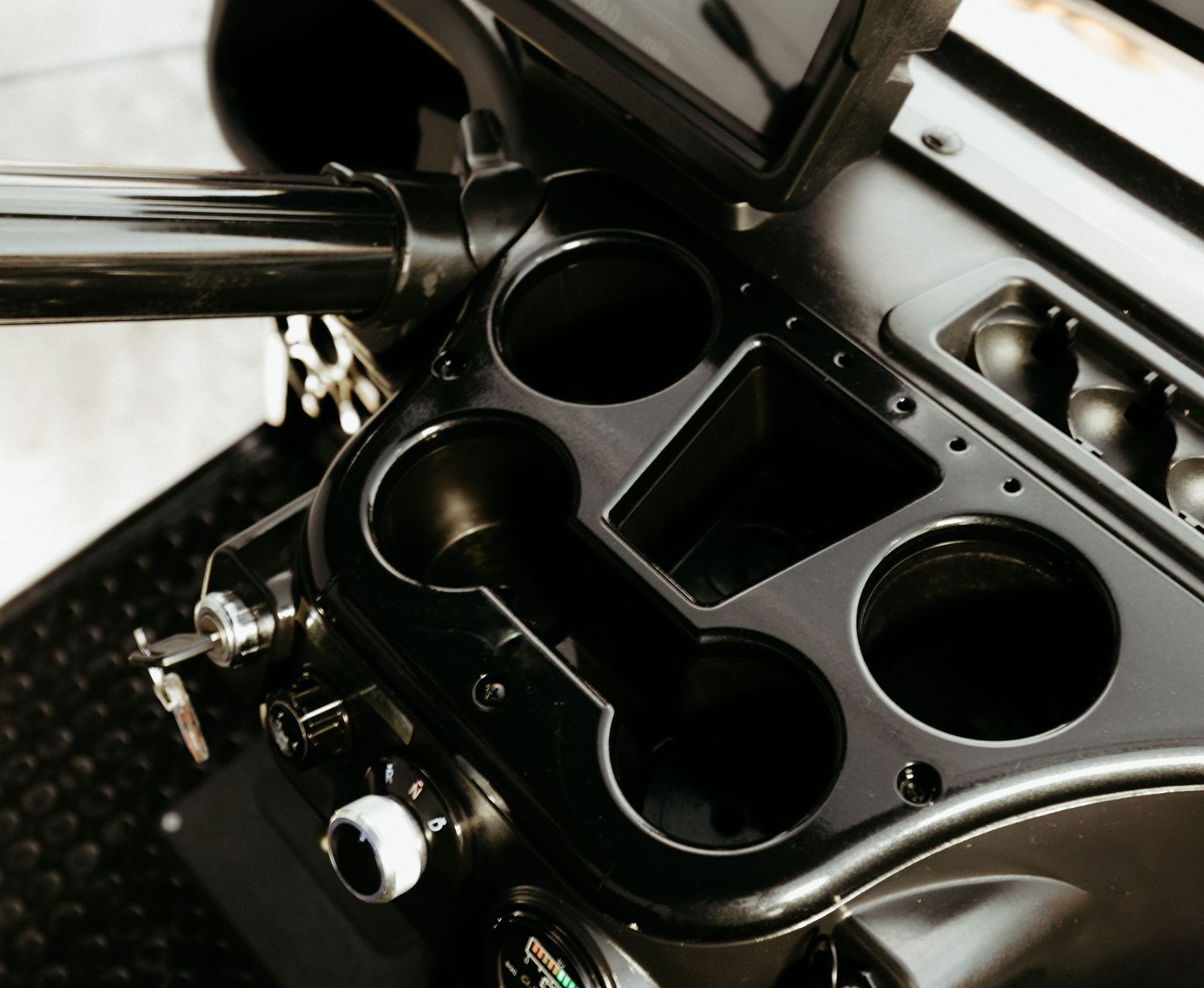 Close-up view of a black car center console with cupholders and metallic accents.