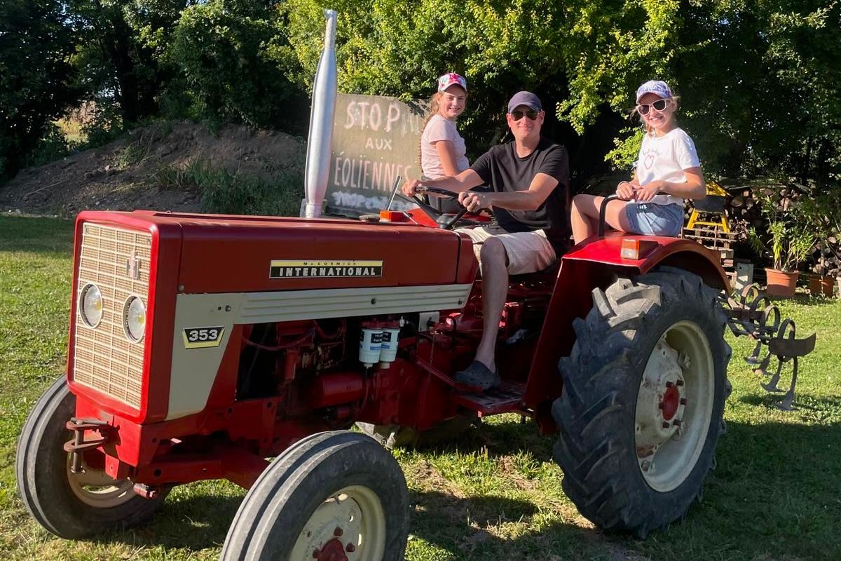 Vintage red International Harvester tractor being operated in a sunny garden setting.