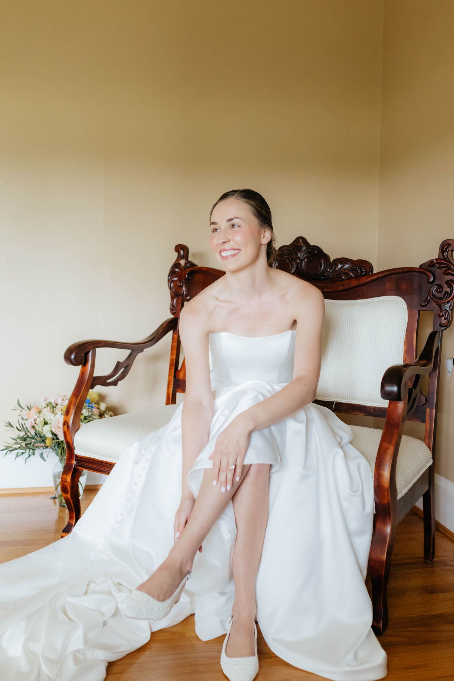 Elegant bridal portraits on an antique wooden chair showing details of a white wedding gown.
