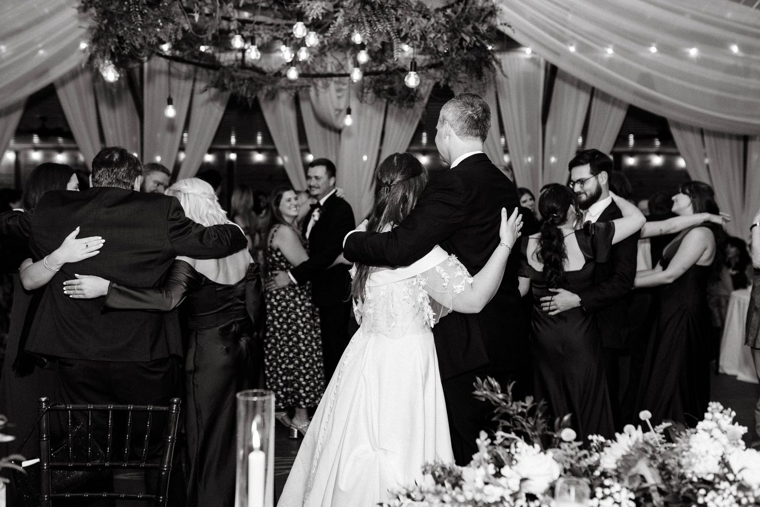 Wedding reception celebration under draped fabric ceiling with string lights.