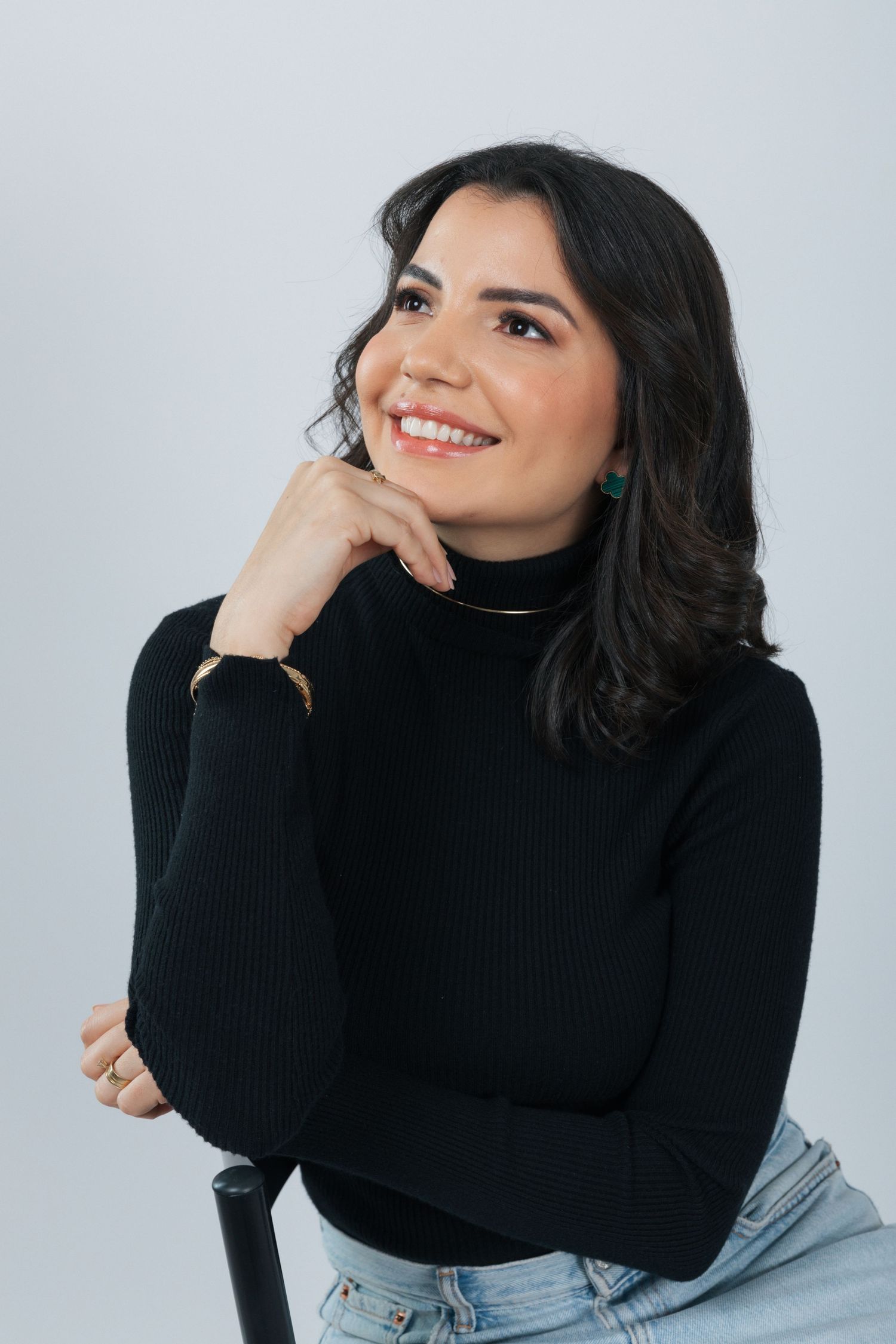 Casual portrait in black turtleneck with hand resting on chin and natural smile.