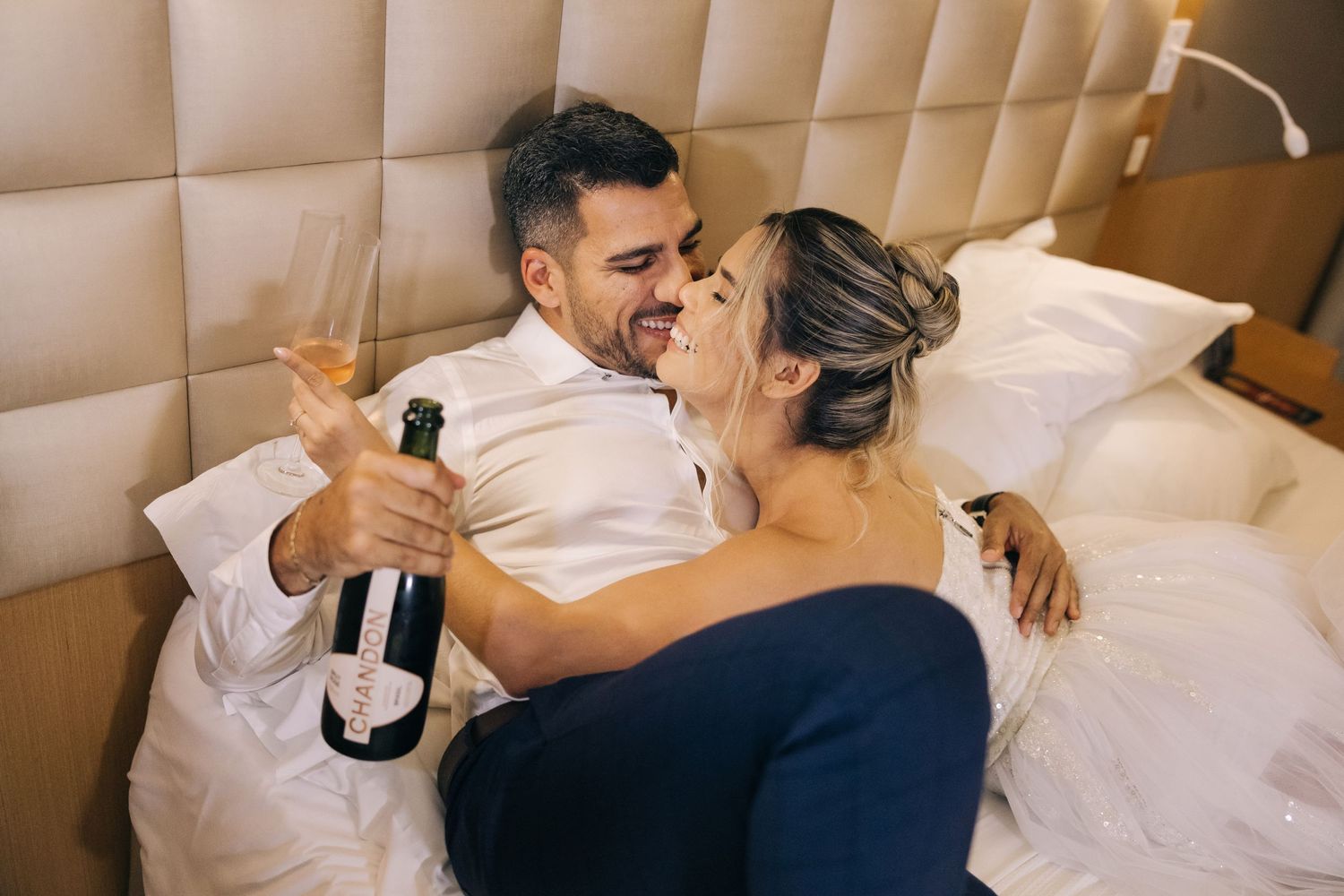 A romantic celebration with champagne on a luxurious upholstered bed.