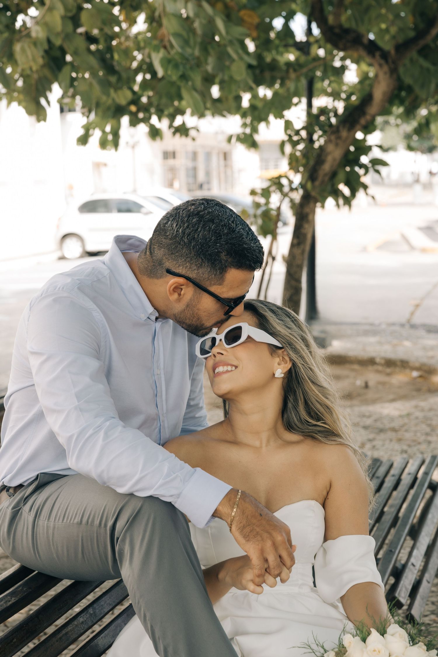 A tender moment shared between a couple sitting on a park bench.