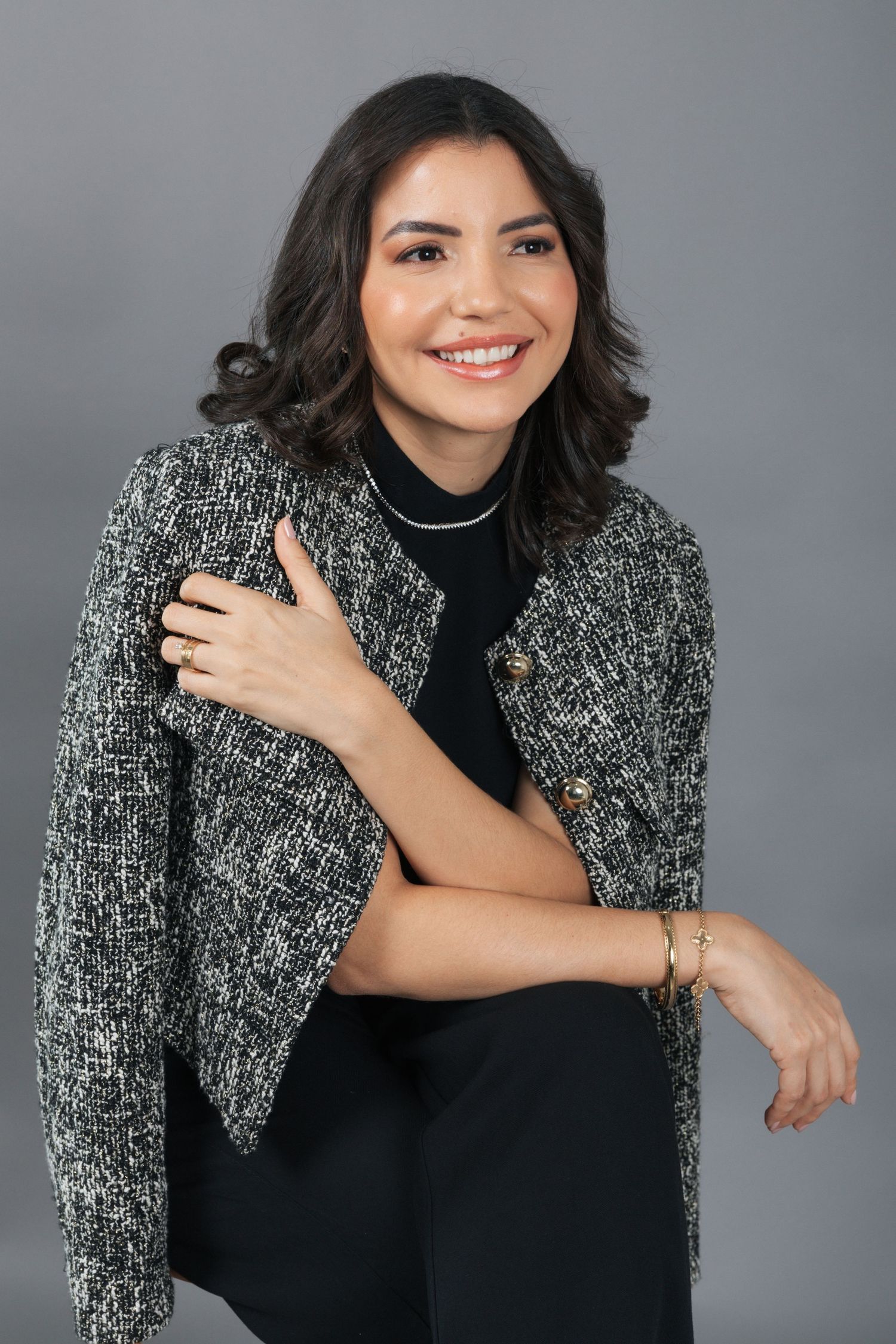 Stylish portrait featuring tweed jacket over black top with modern jewelry accents.