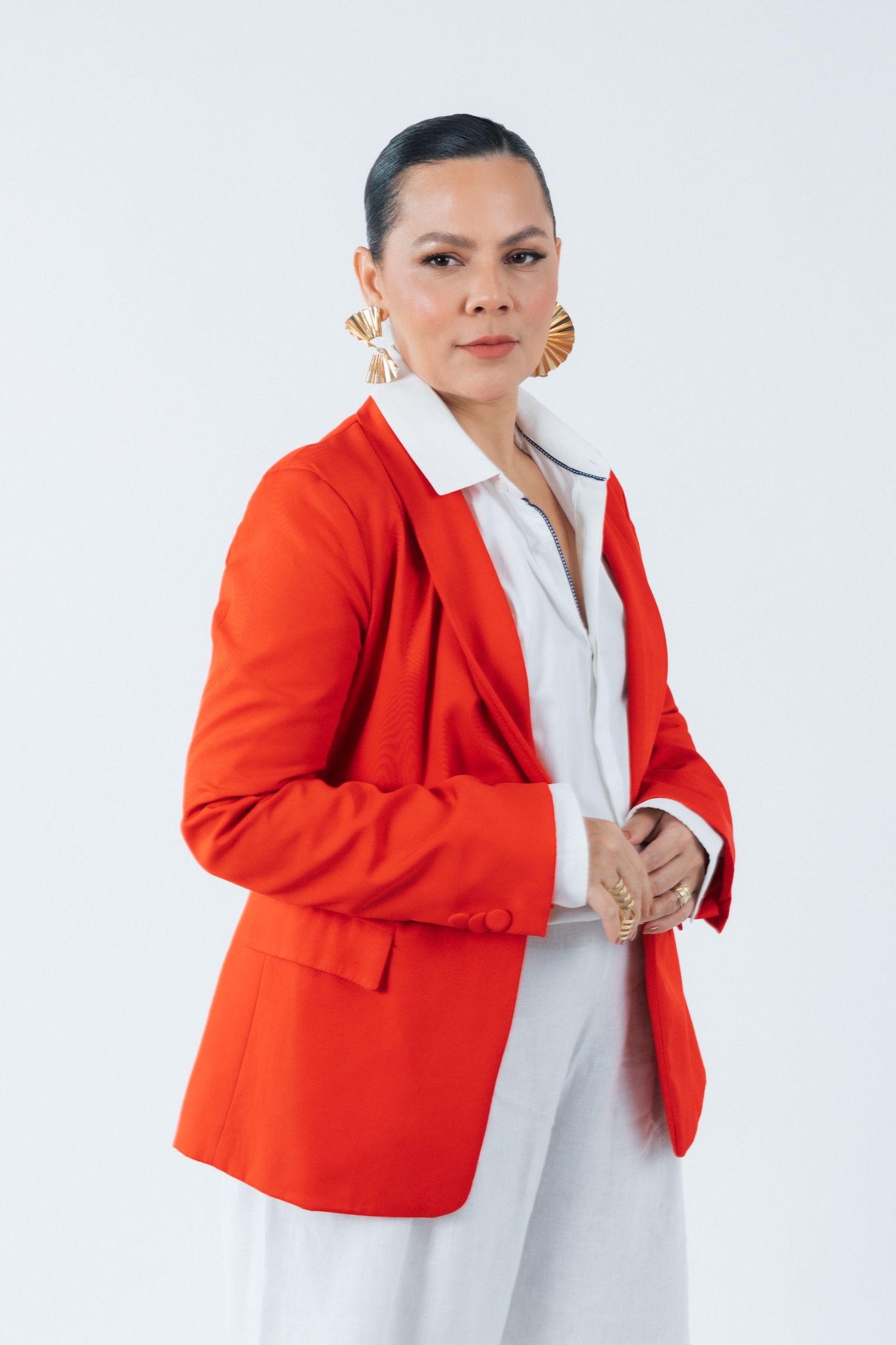Model wearing vibrant red blazer with white collared shirt in professional studio portrait.