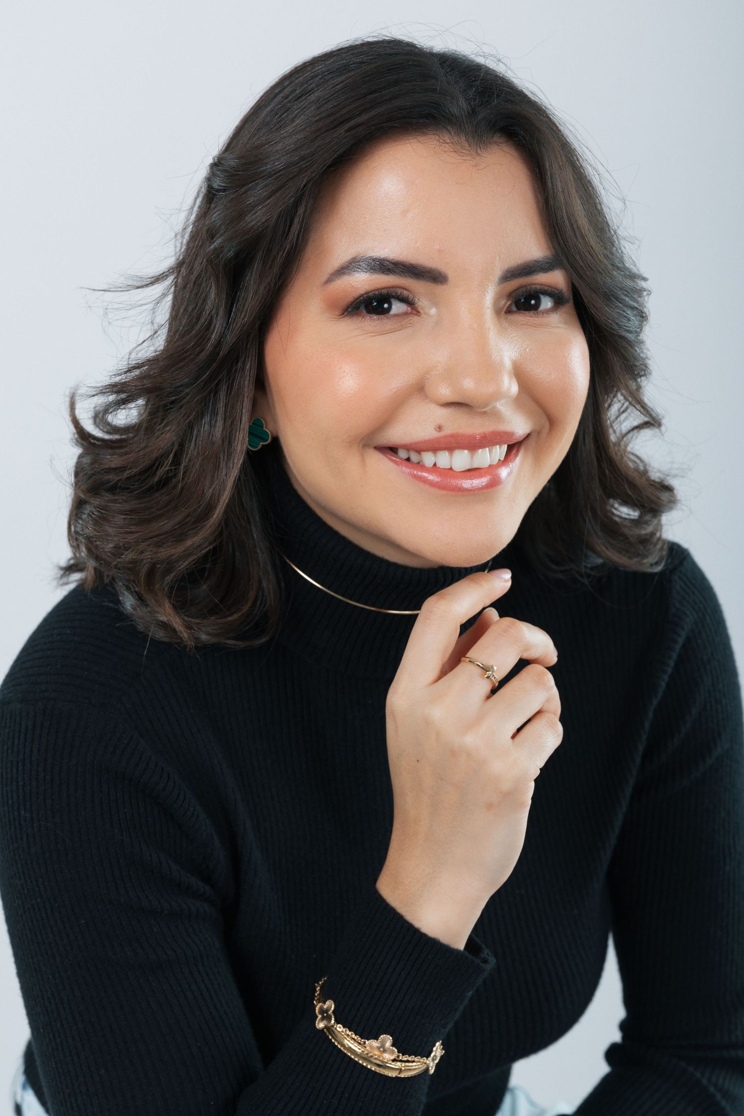 Stylish portrait in black turtleneck with turquoise earrings and gold bracelet.