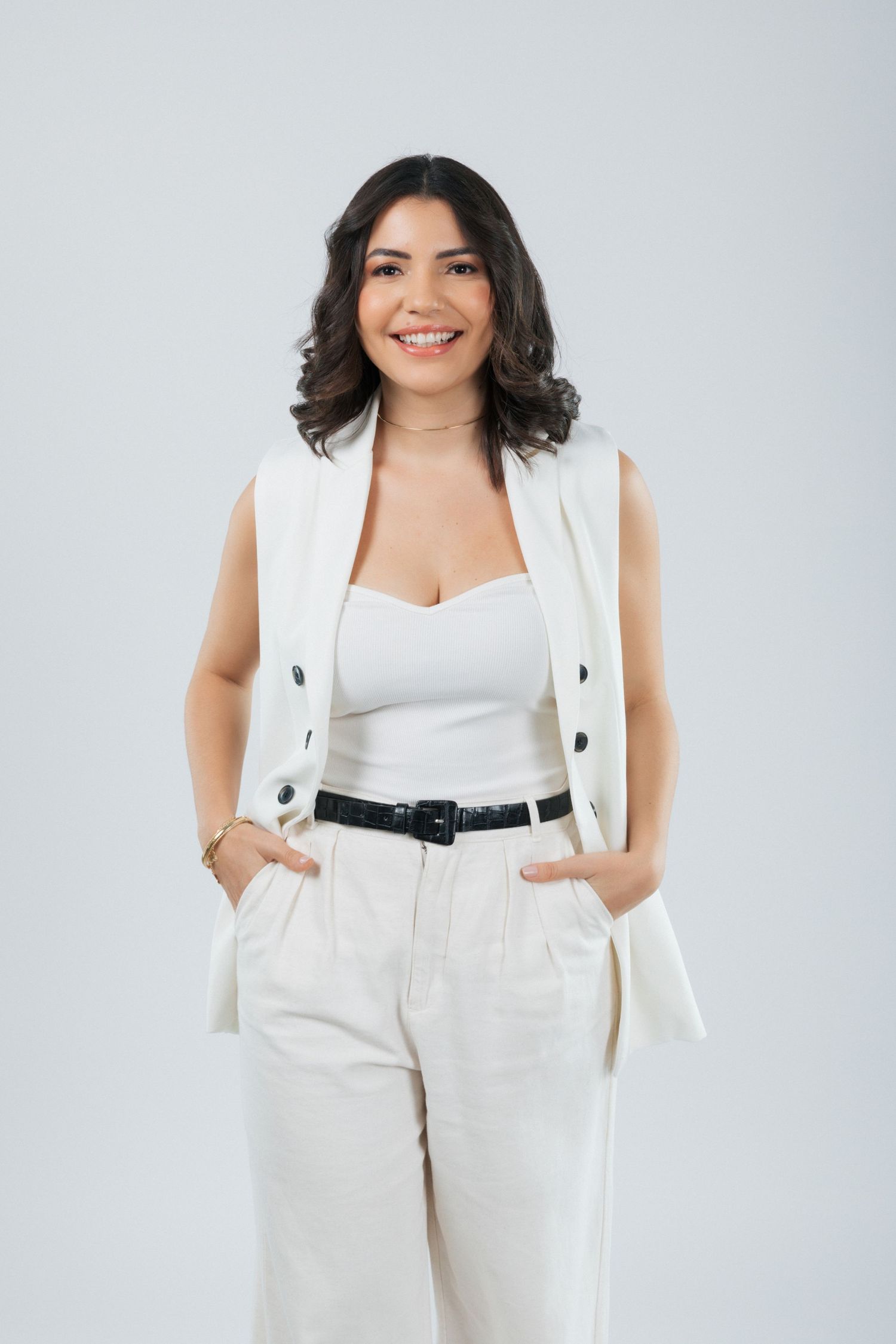 Modern business look with white vest, tank top and high-waisted pants with belt.