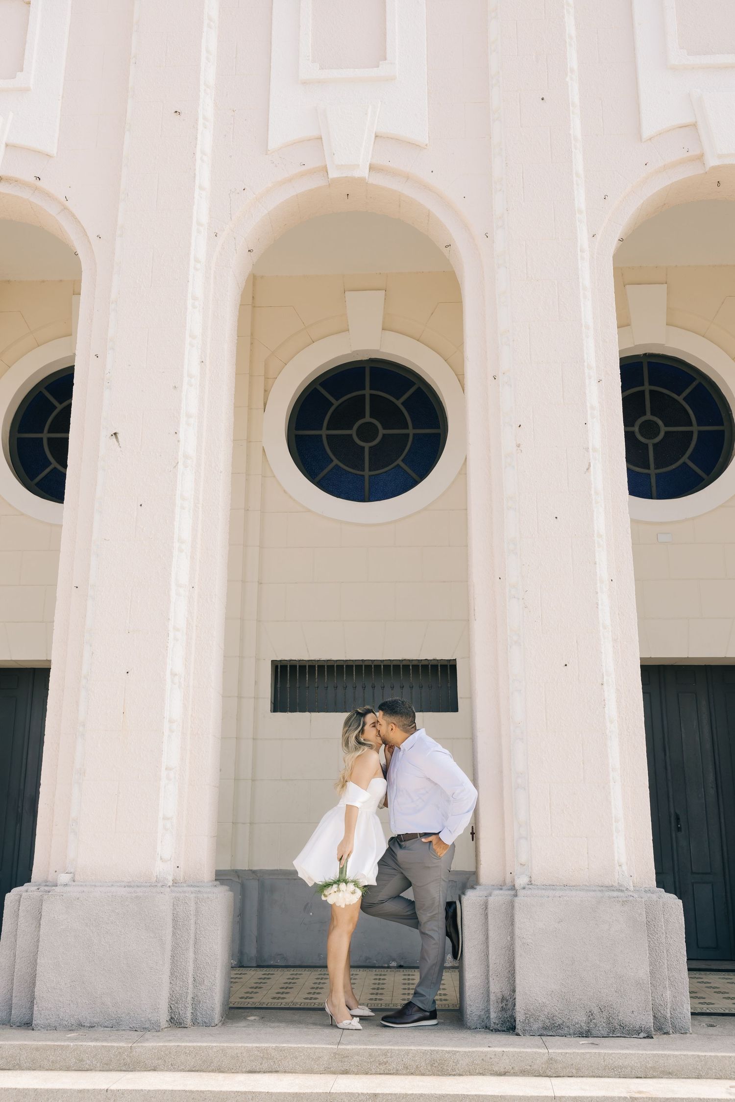 A romantic moment shared under grand arched windows of a classic building.