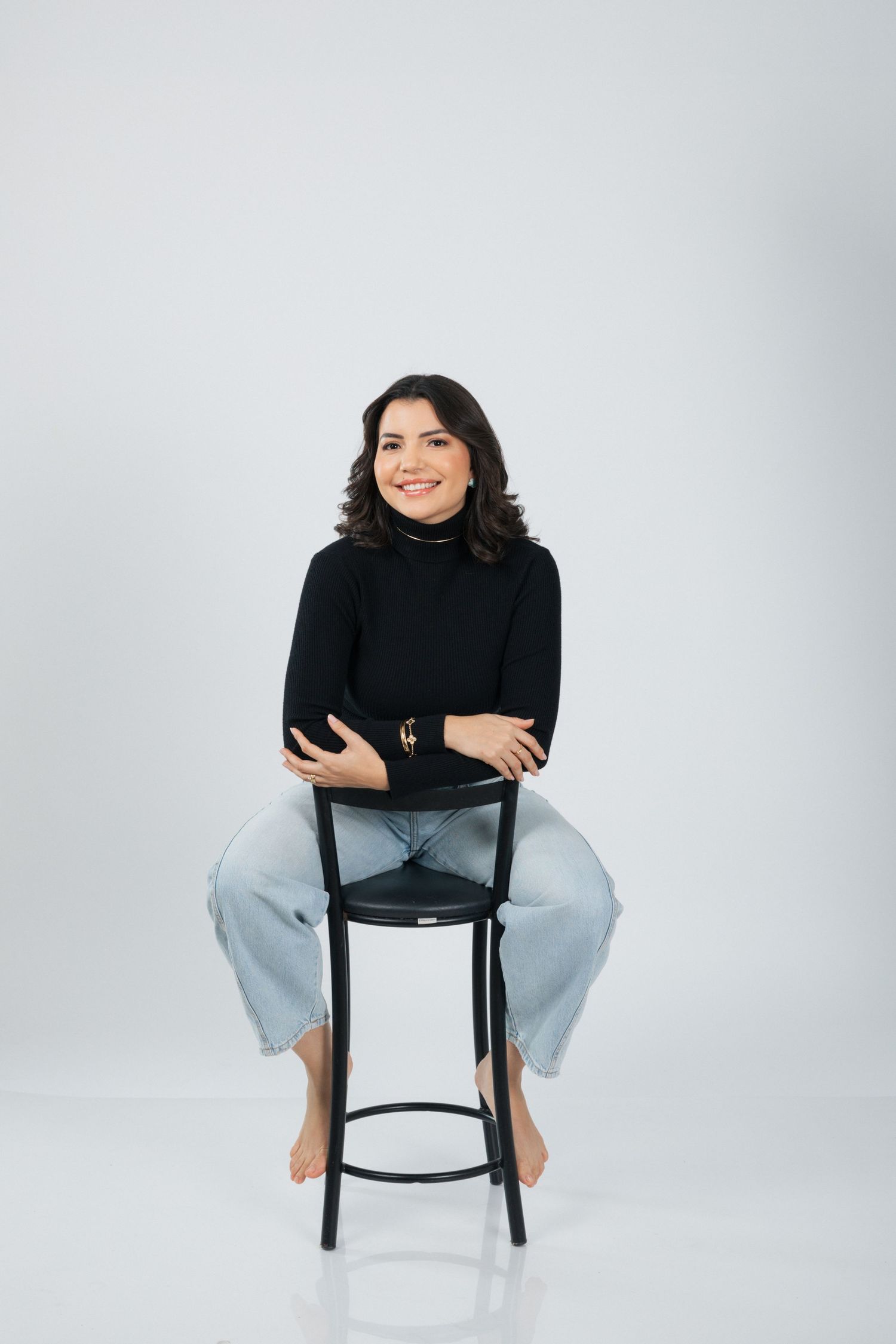 Studio portrait in black turtleneck sweater sitting casually on a barstool.
