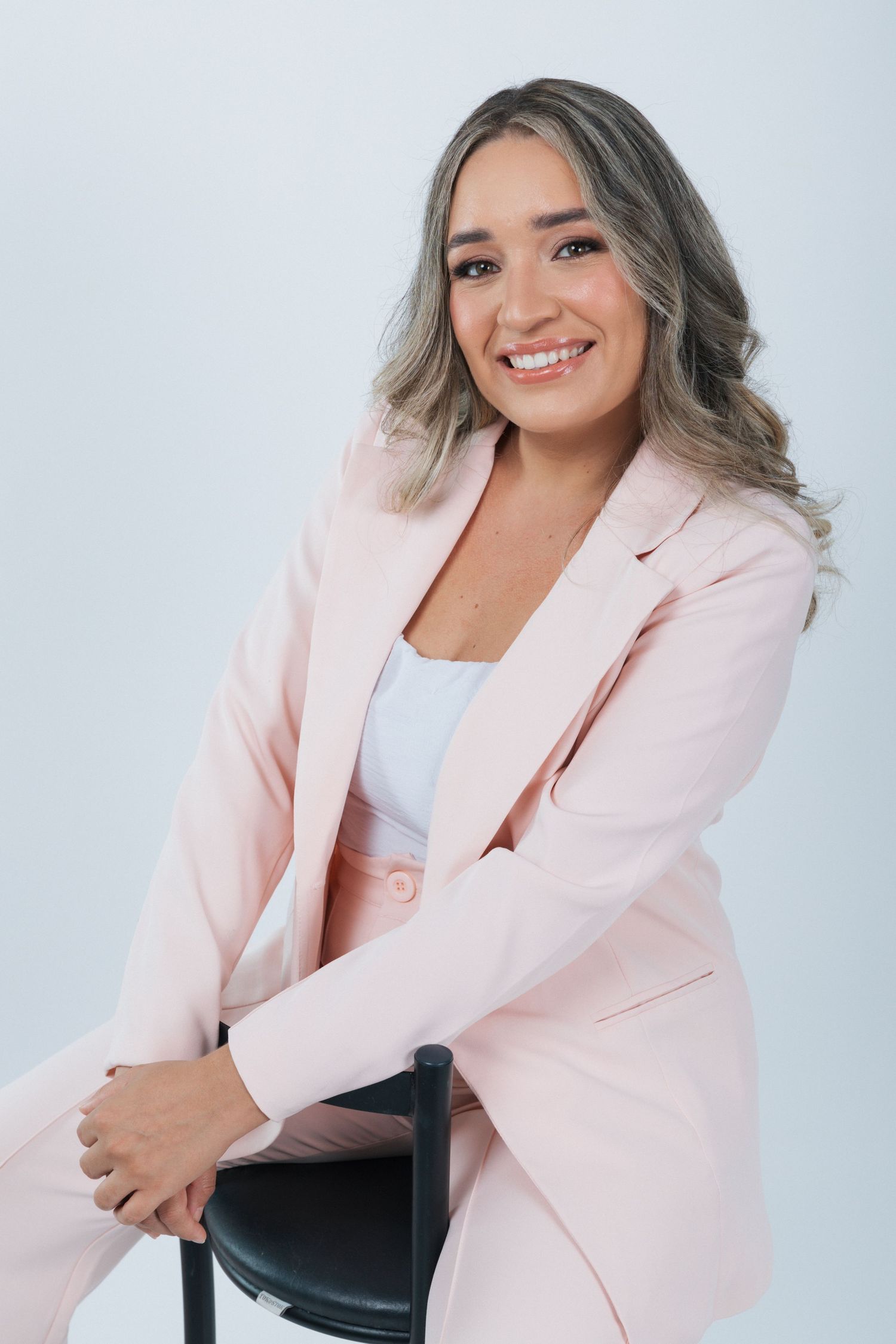 Professional portrait of someone wearing a light pink blazer and white top against a light background.