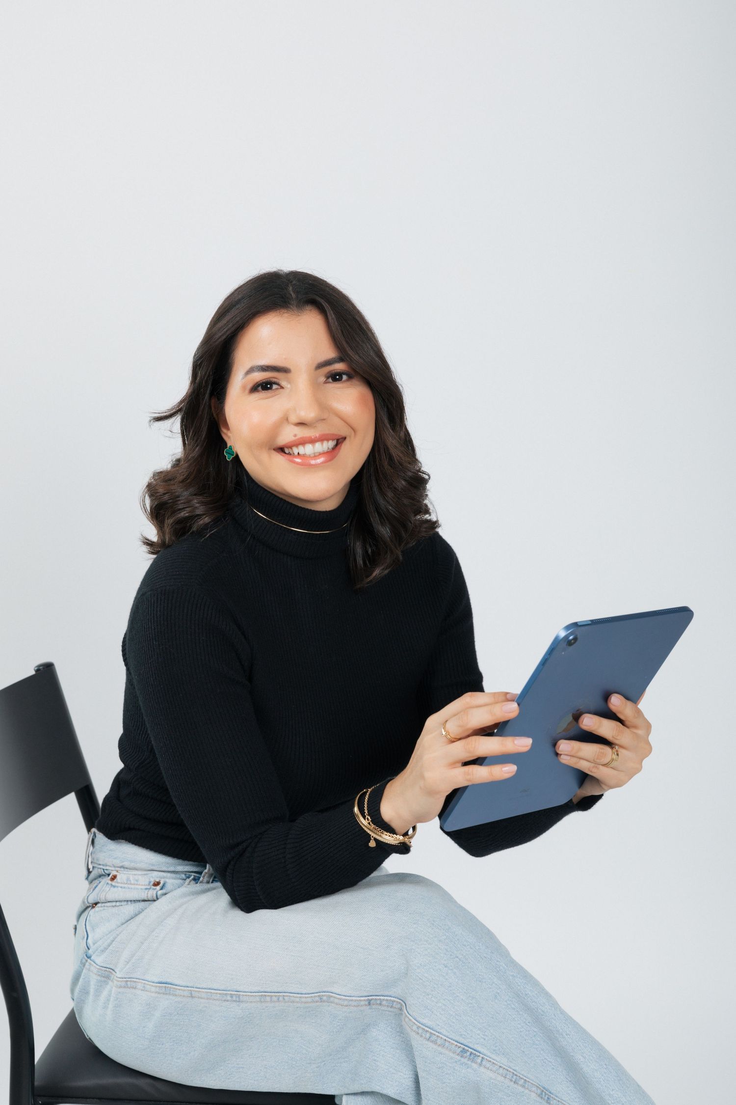 Business casual look with black turtleneck while holding tablet device and smiling.
