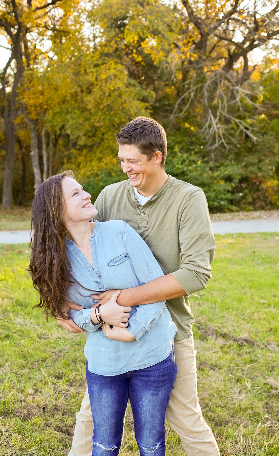Couple laughs together during playful moment in autumn park.