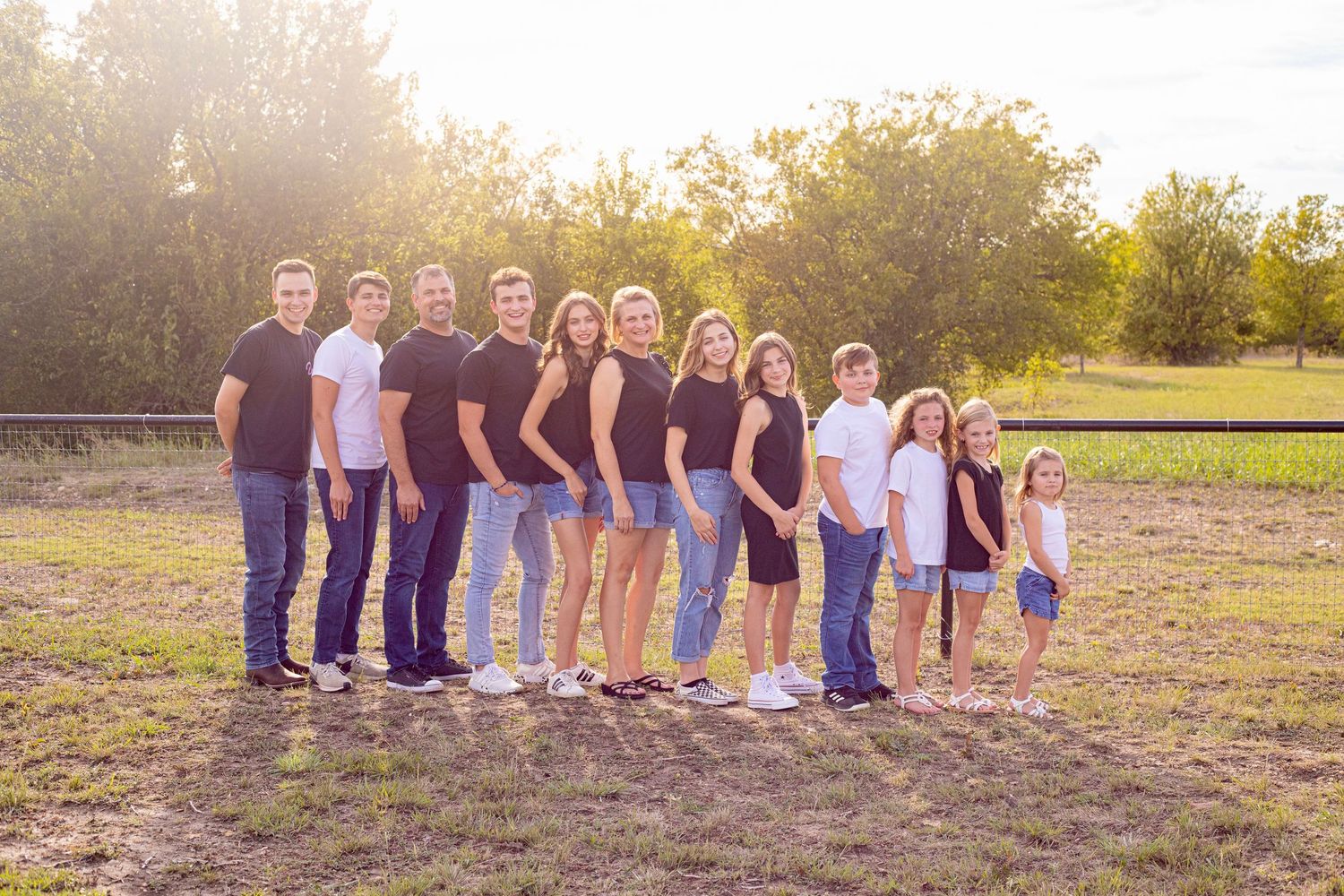 Large group portrait session at sunset in a rustic outdoor setting.