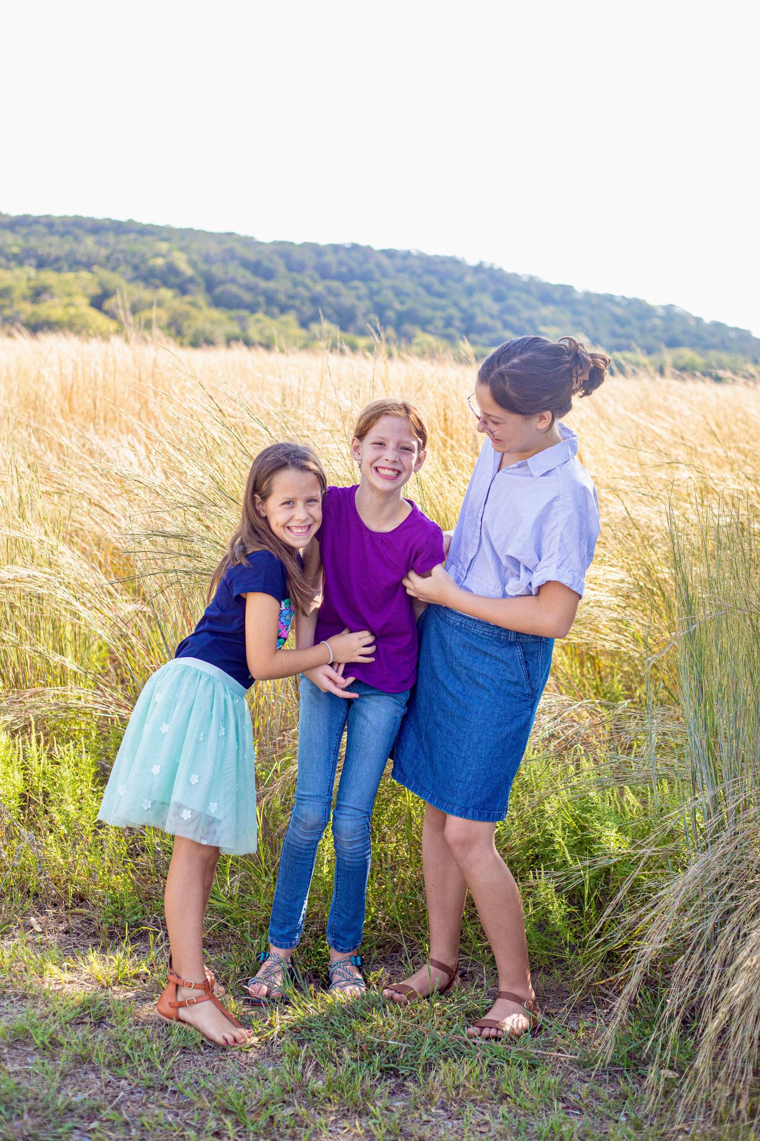 Candid laughter shared between siblings in a natural outdoor setting.