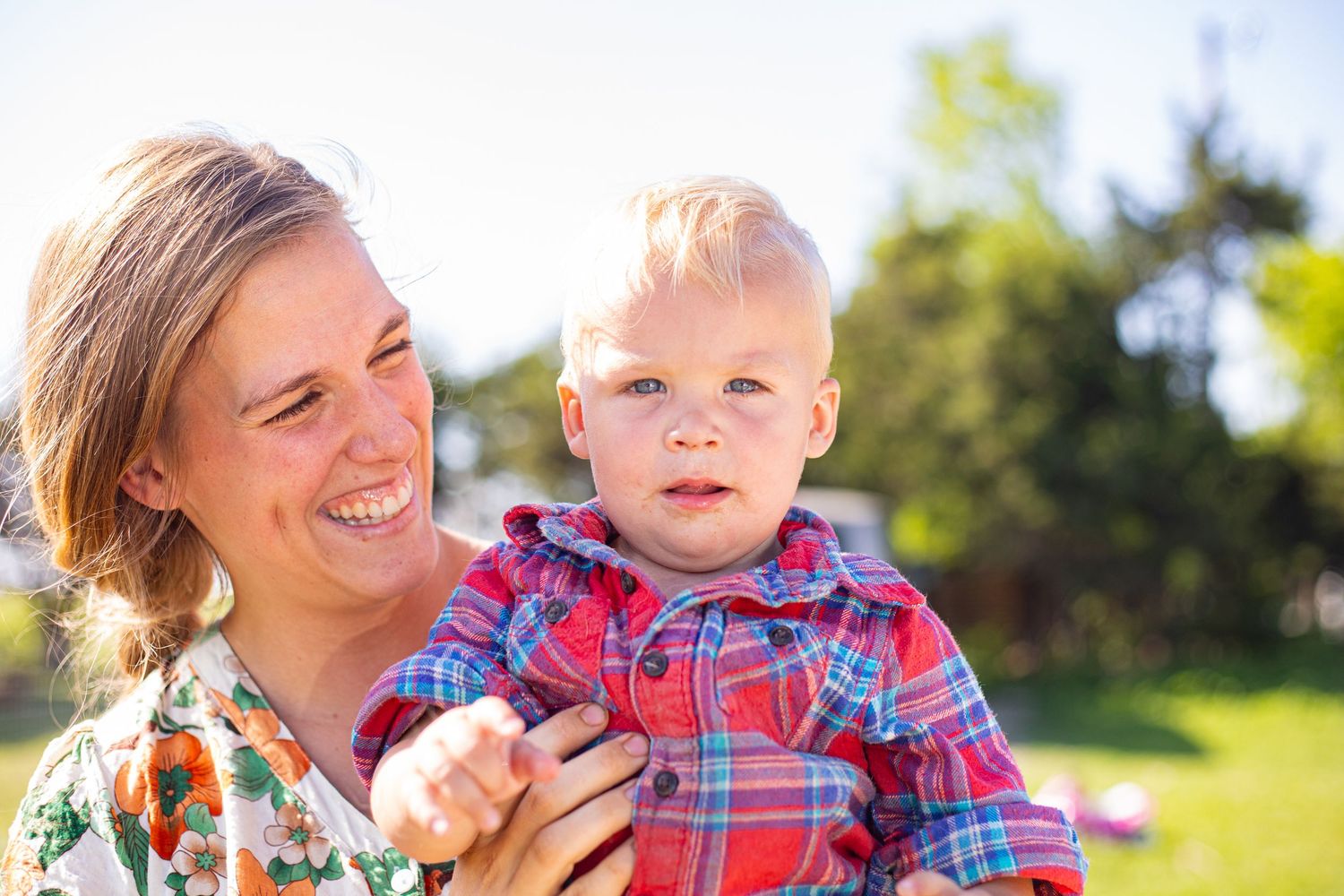 Mother and child sharing joyful moments outdoors in bright sunlight.
