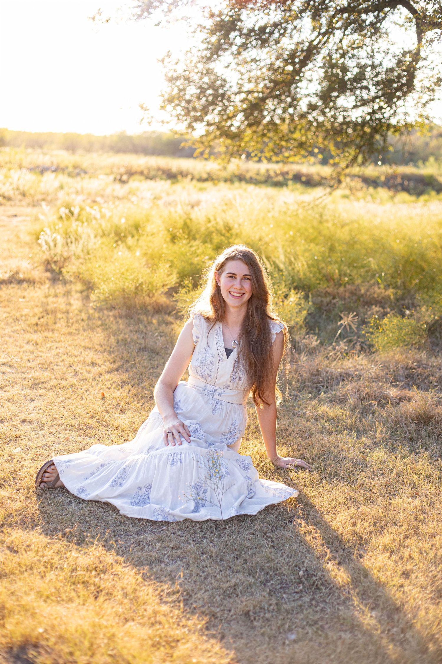 Outdoor portrait session in white dress against warm sunset lighting.