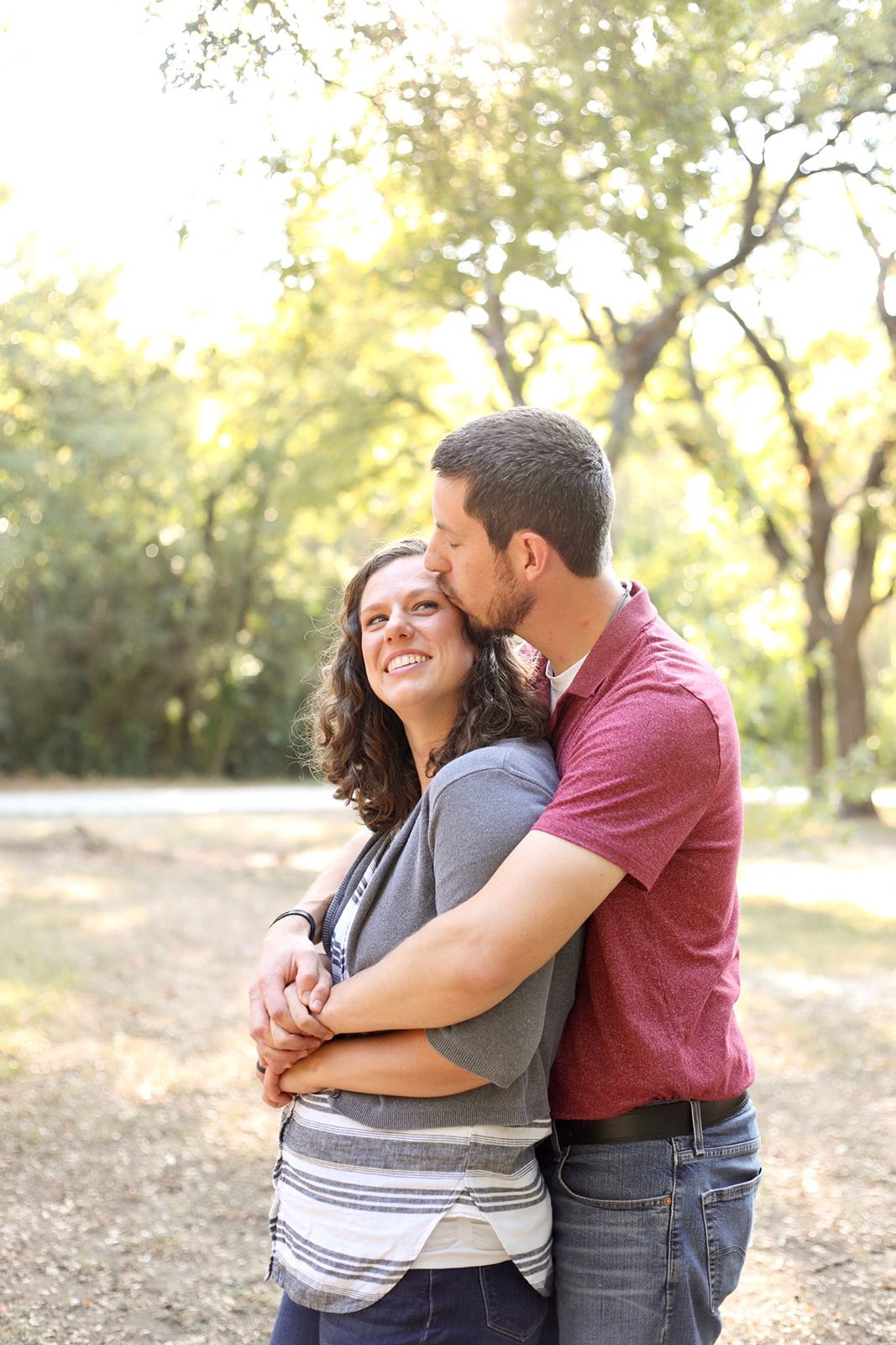 Couple sharing playful embrace outdoors in casual attire.
