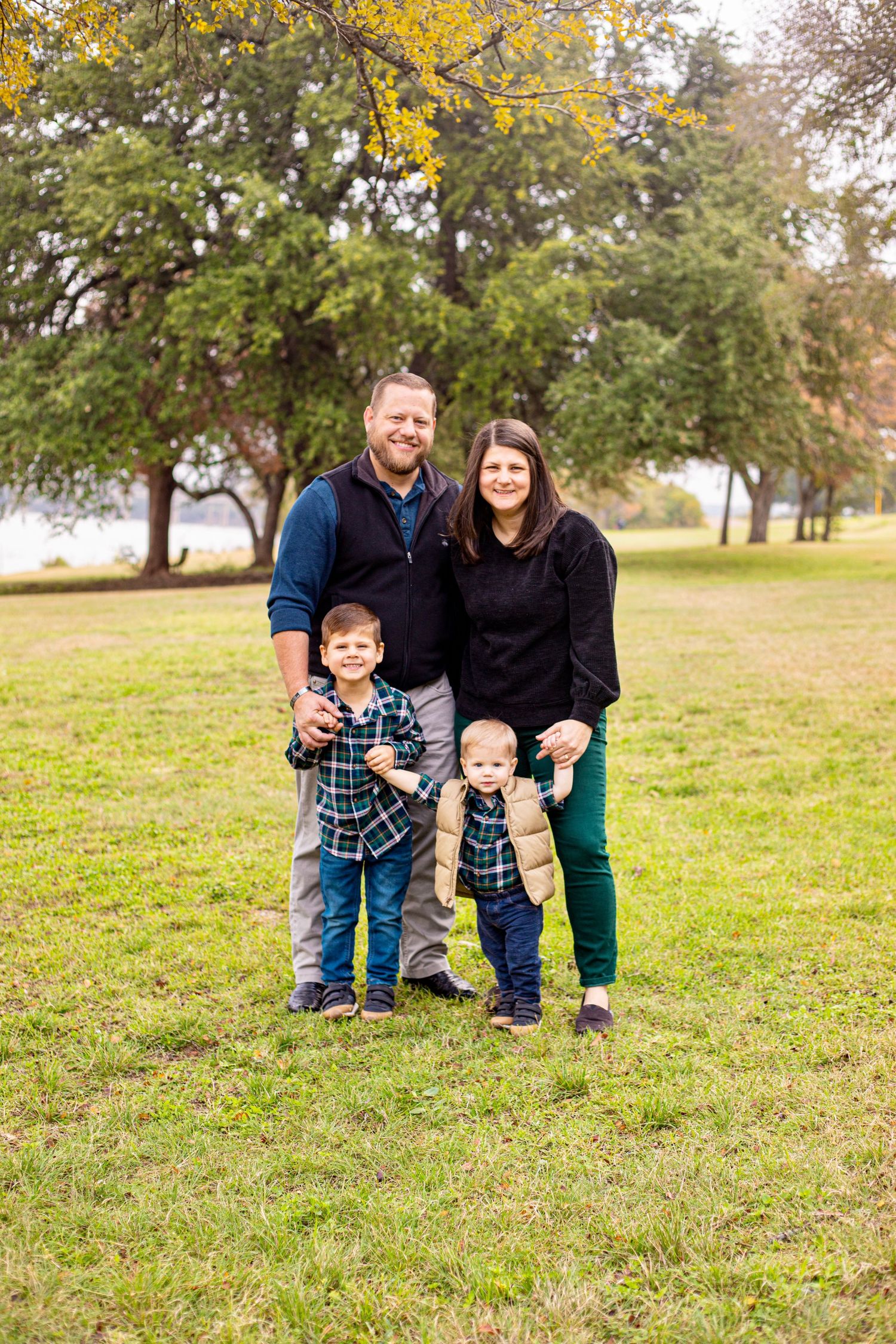 Family enjoying a playful moment together on a grassy hill during autumn.