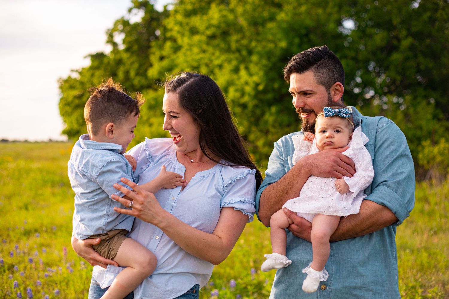 Candid moments of parents playing with their baby in a sunny meadow.