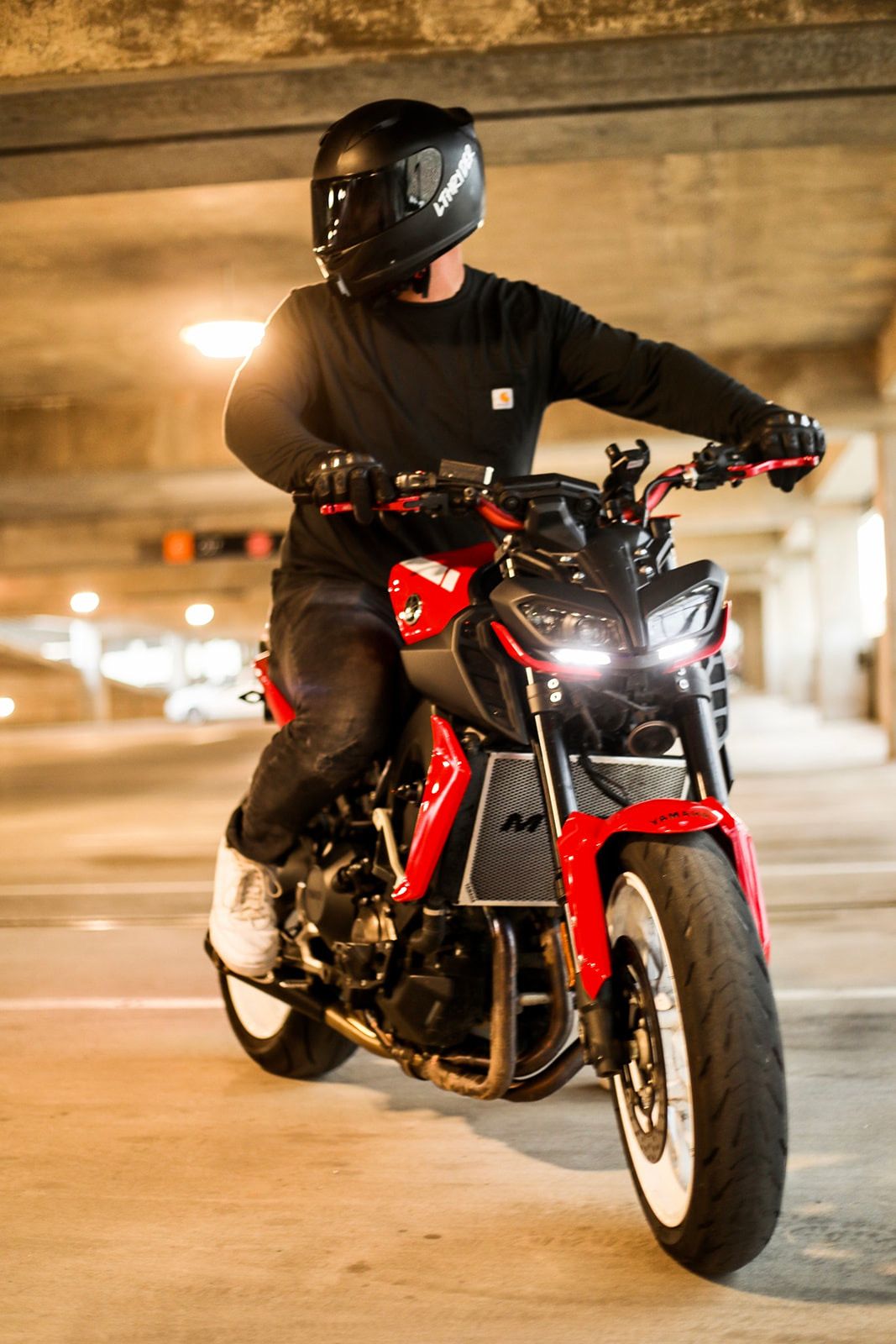 Red and black motorcycle photographed in sequence in dimly lit parking garage.