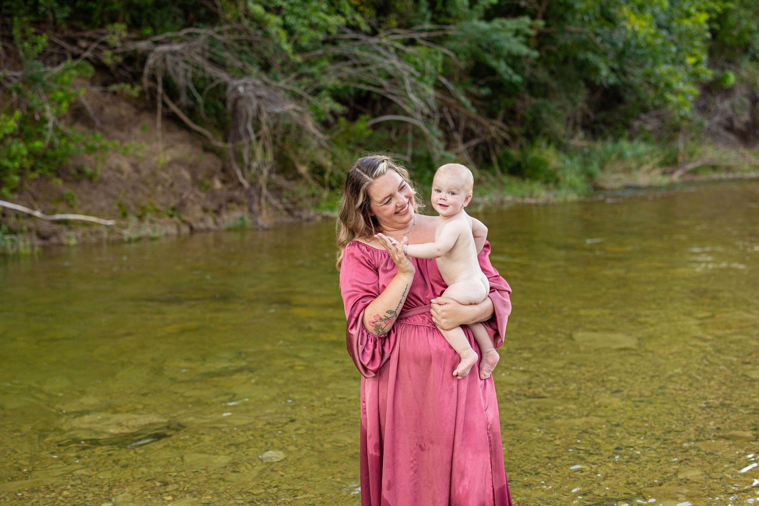 Sweet interaction between two figures in matching mauve dresses near a river.