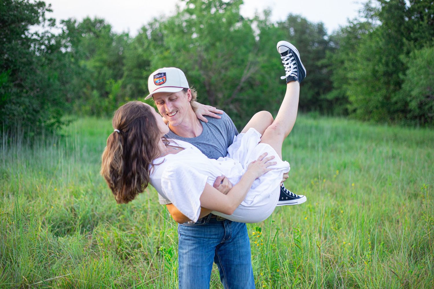 Playful couple in casual wear having fun in grassy meadow.