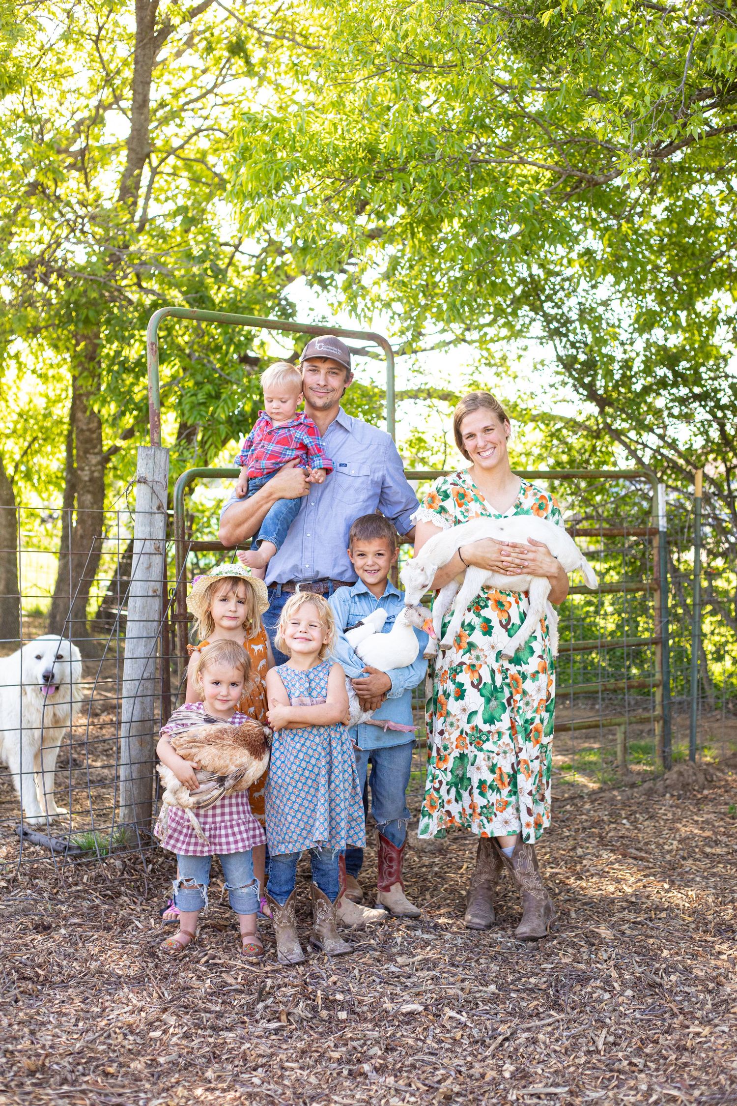 Family portrait in wooded setting with natural sunlight filtering through trees.