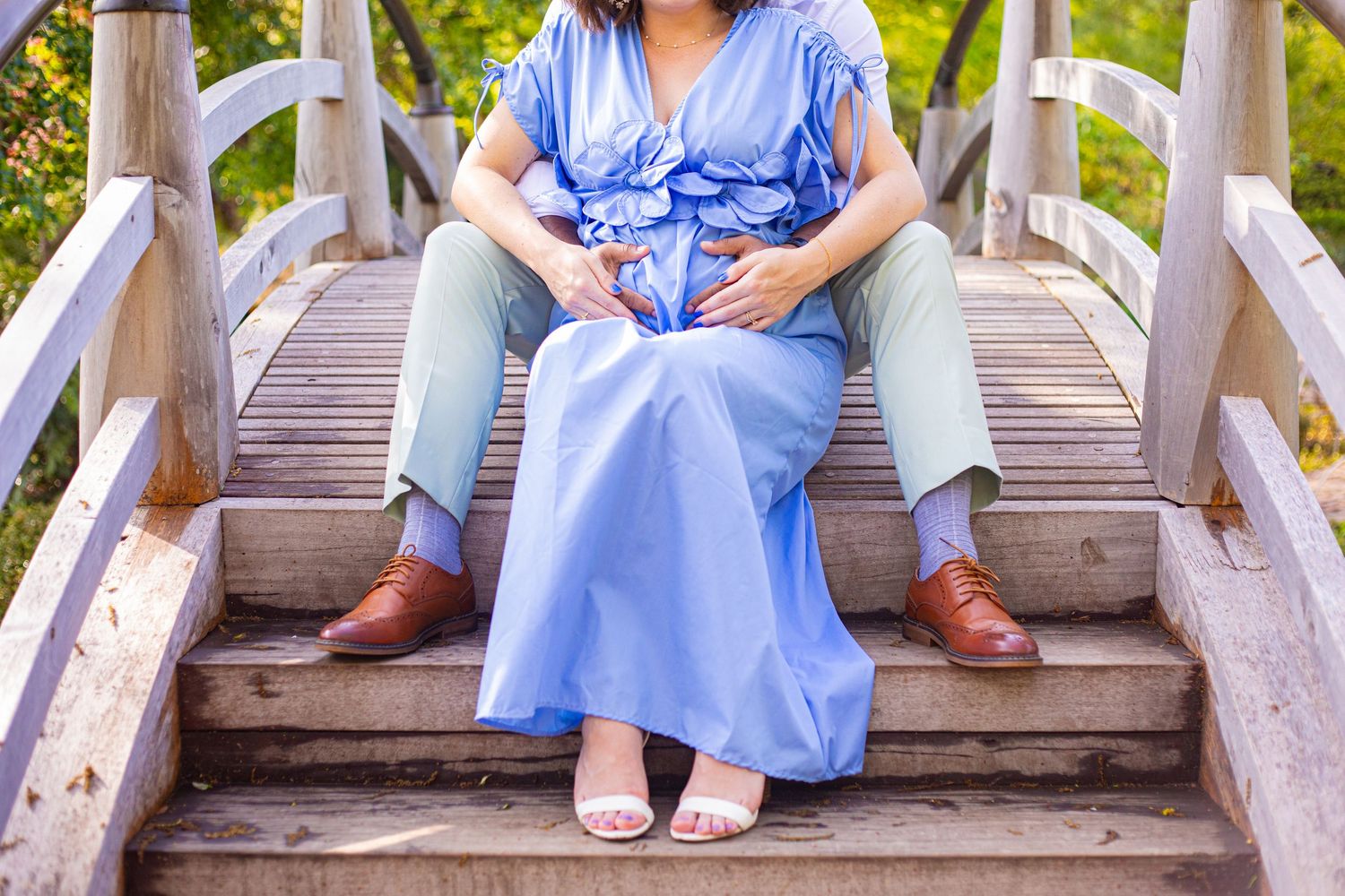 Person in blue dress sitting on wooden stairs outdoors.