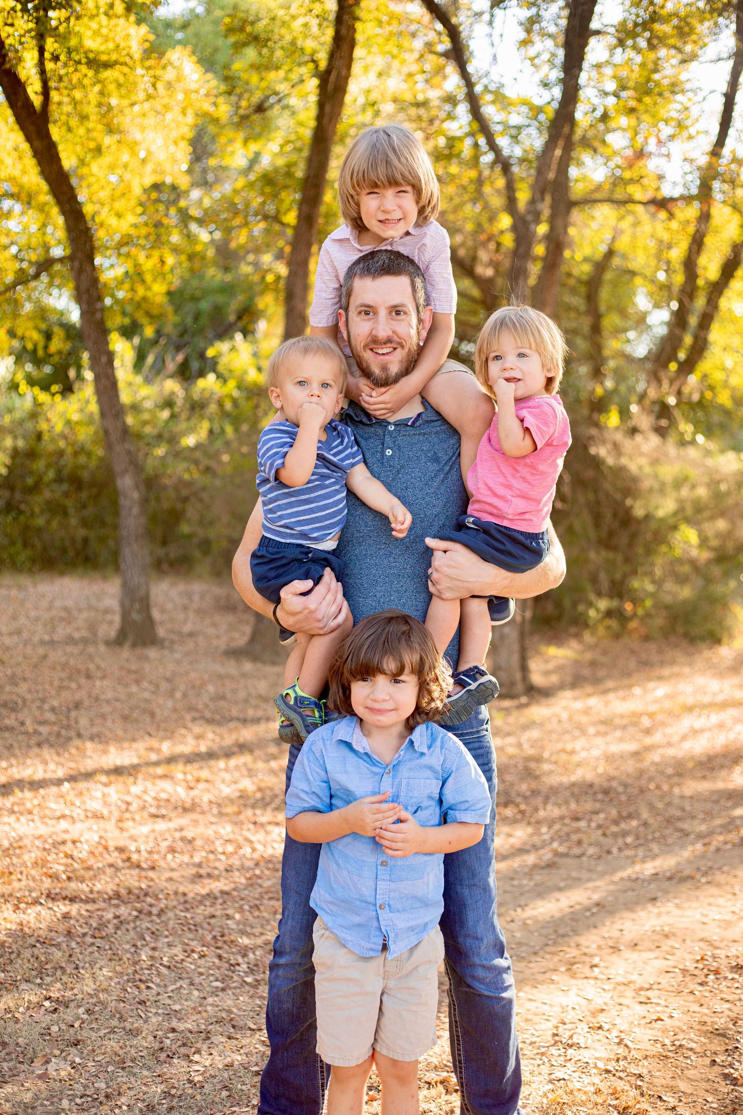 A playful family portrait with everyone stacked together in a wooded setting.