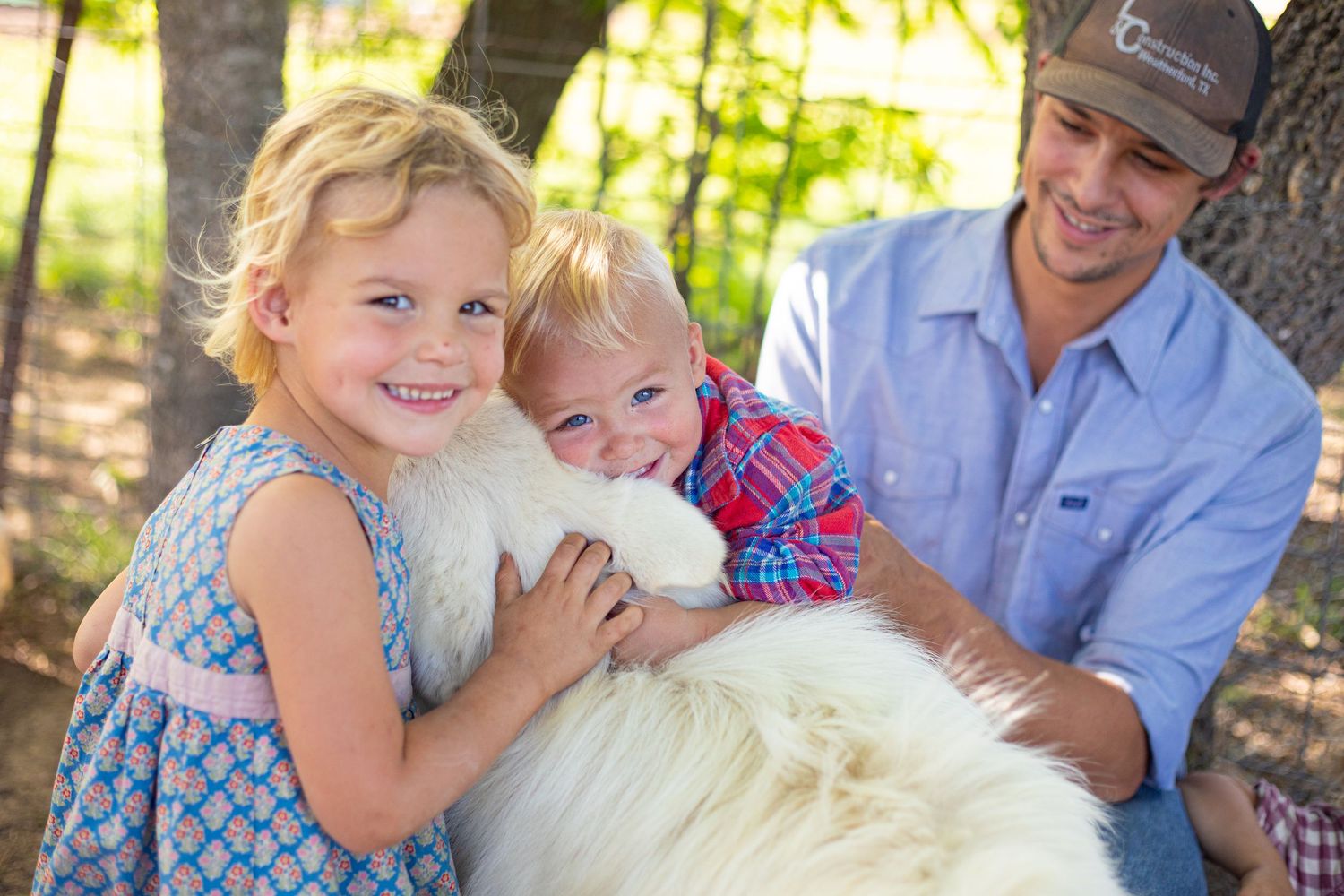 Family spending time with their large white fluffy dog in a forest setting.