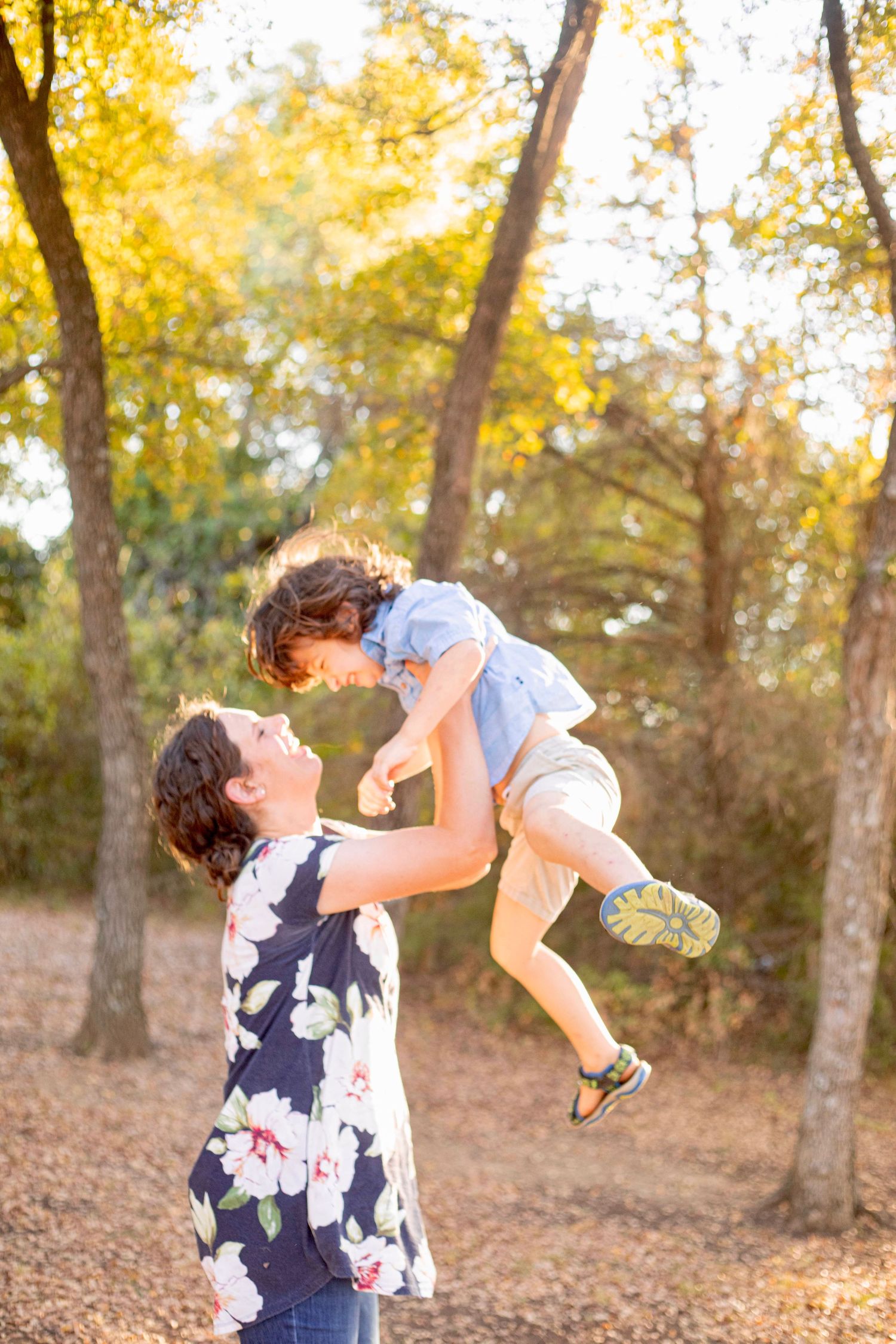 Playful lifting moment between two people in a golden autumn forest setting.