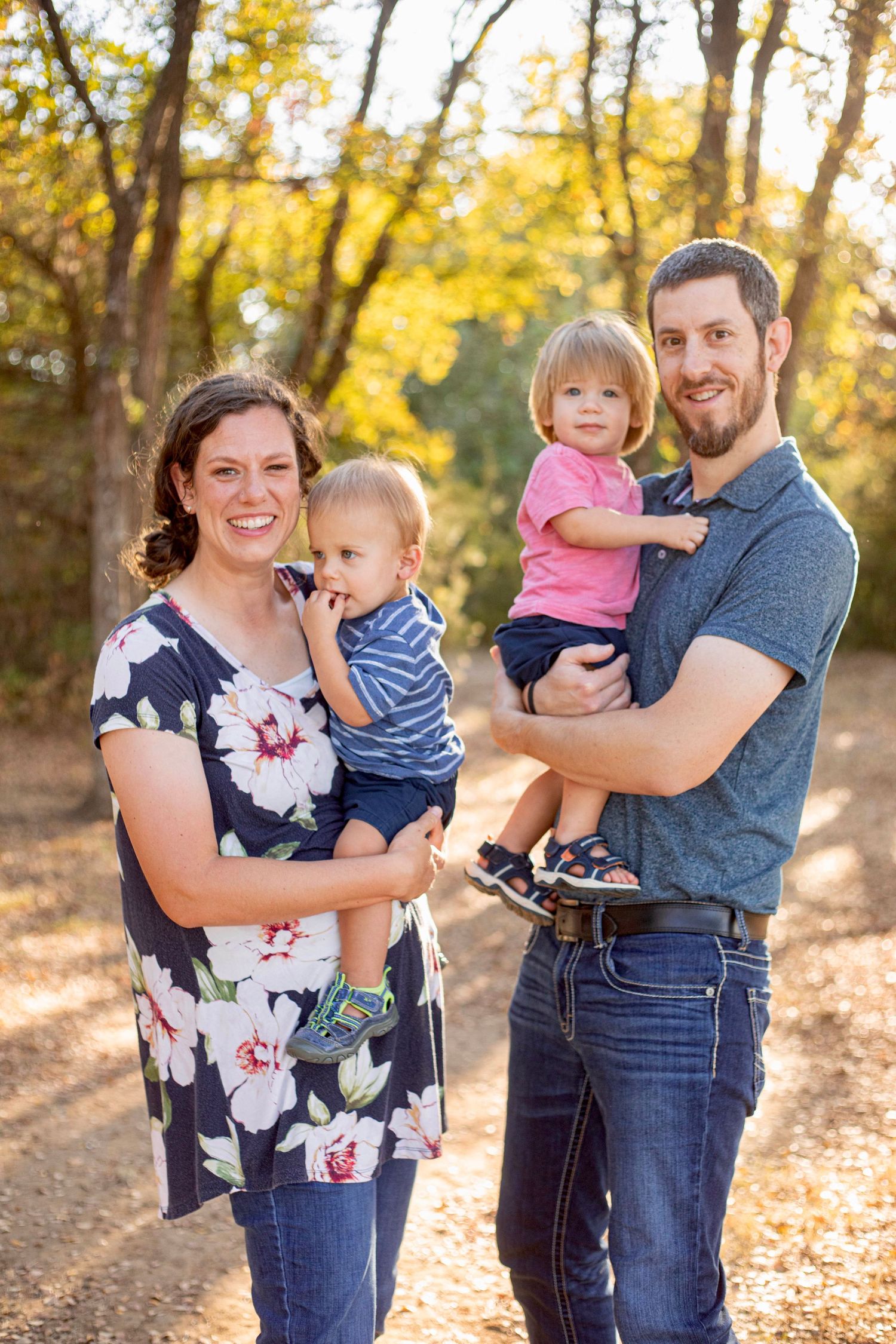 Family portrait series with natural poses in a golden-lit autumn forest setting.