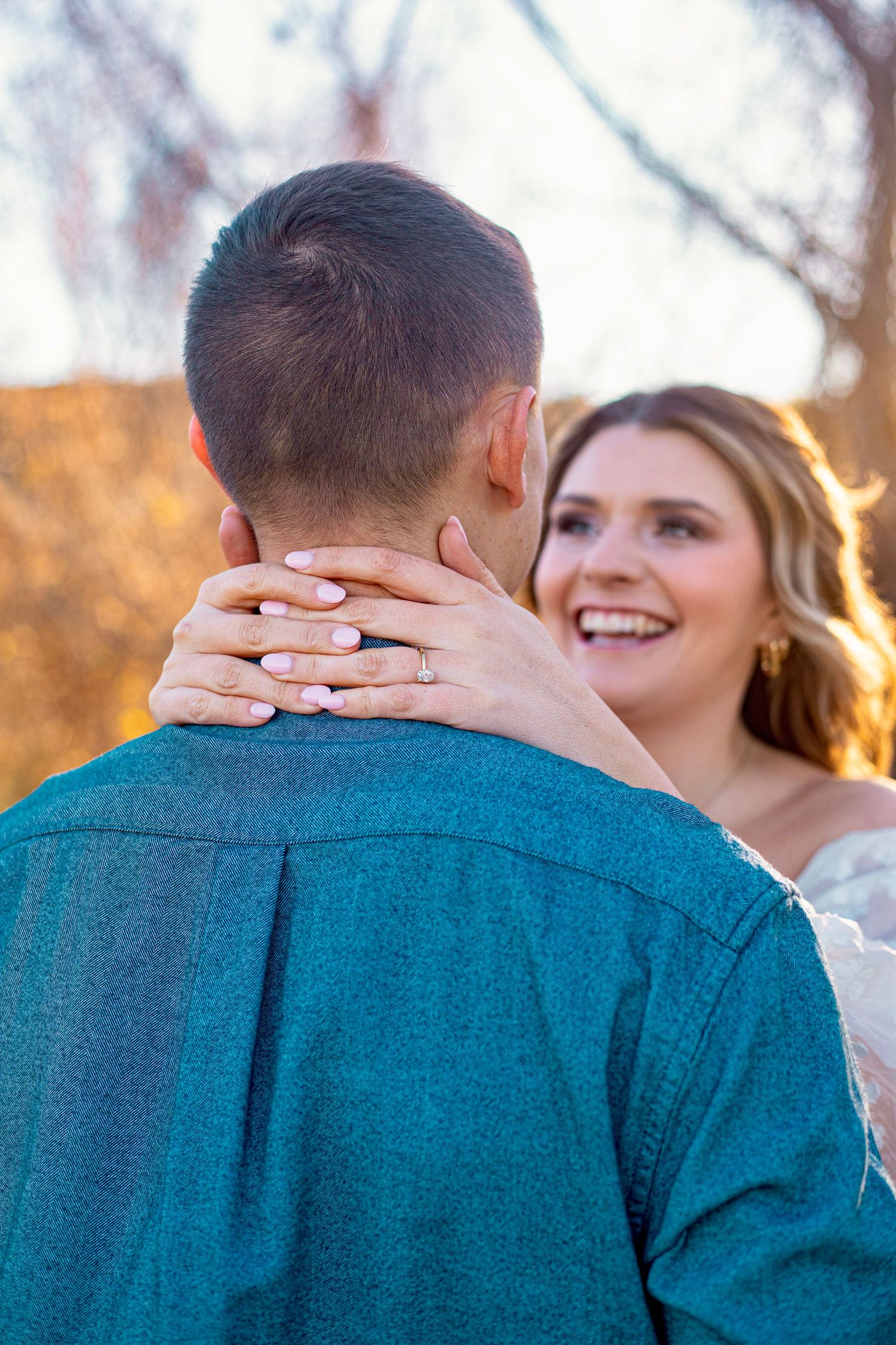 A romantic moment captured from behind as hands wrap around in an embrace during sunset.