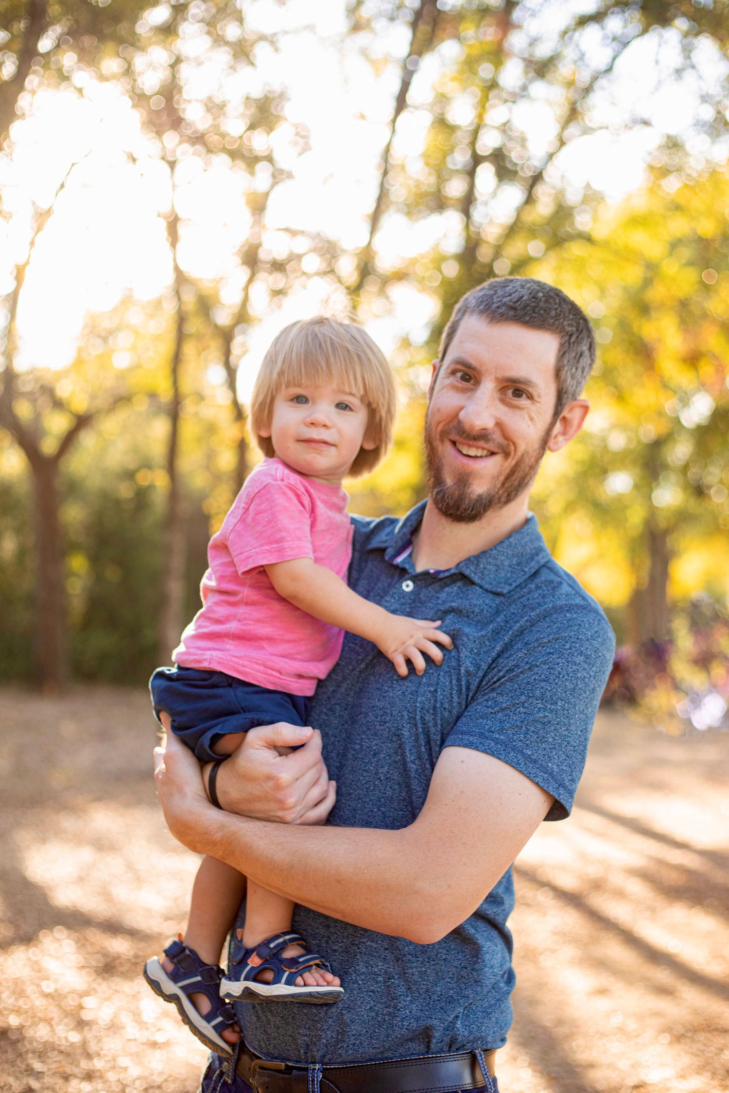 Sweet interaction between parent and child against sunlit autumn forest backdrop.