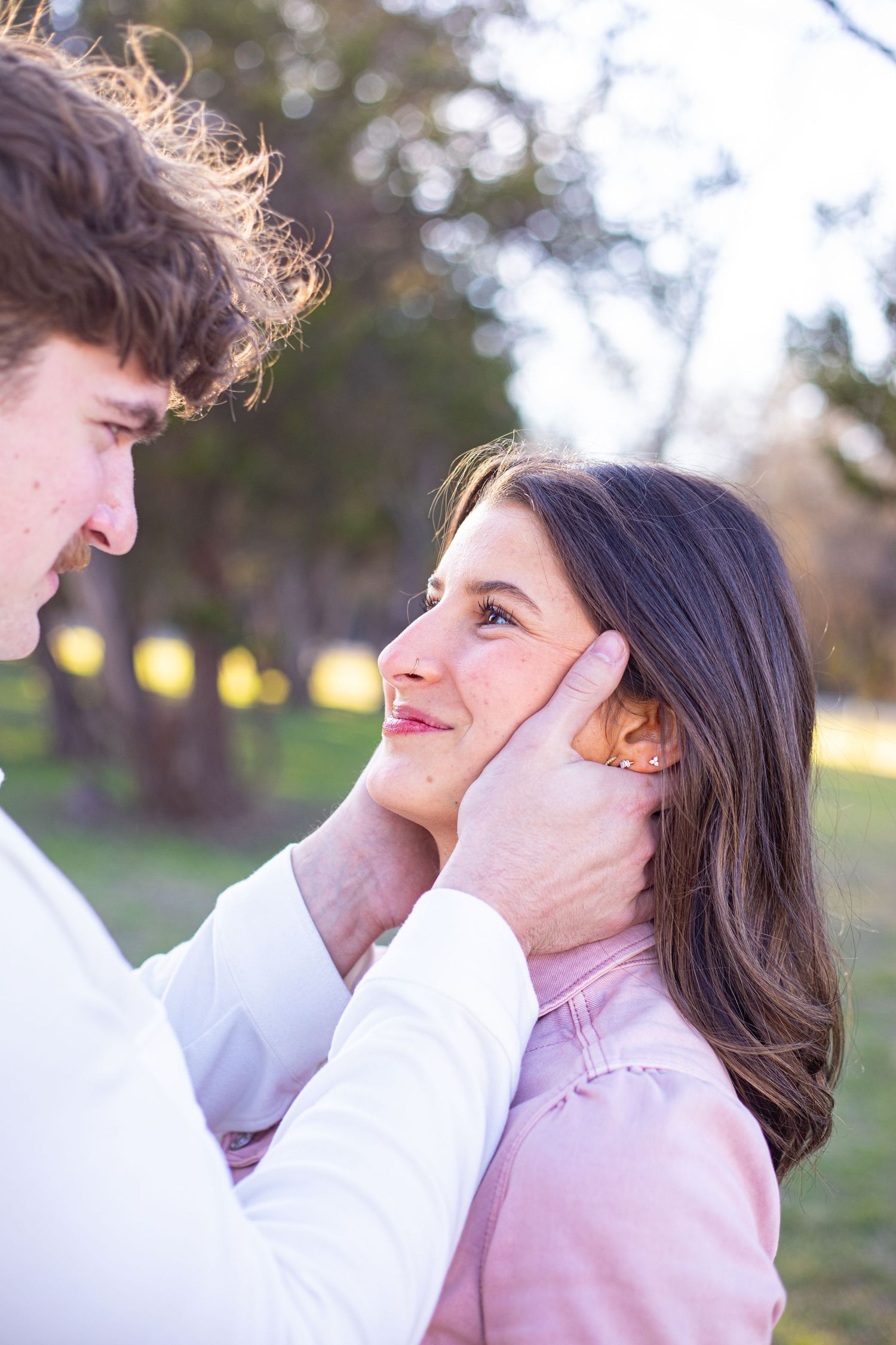 A tender moment between a couple in soft natural lighting outdoors.