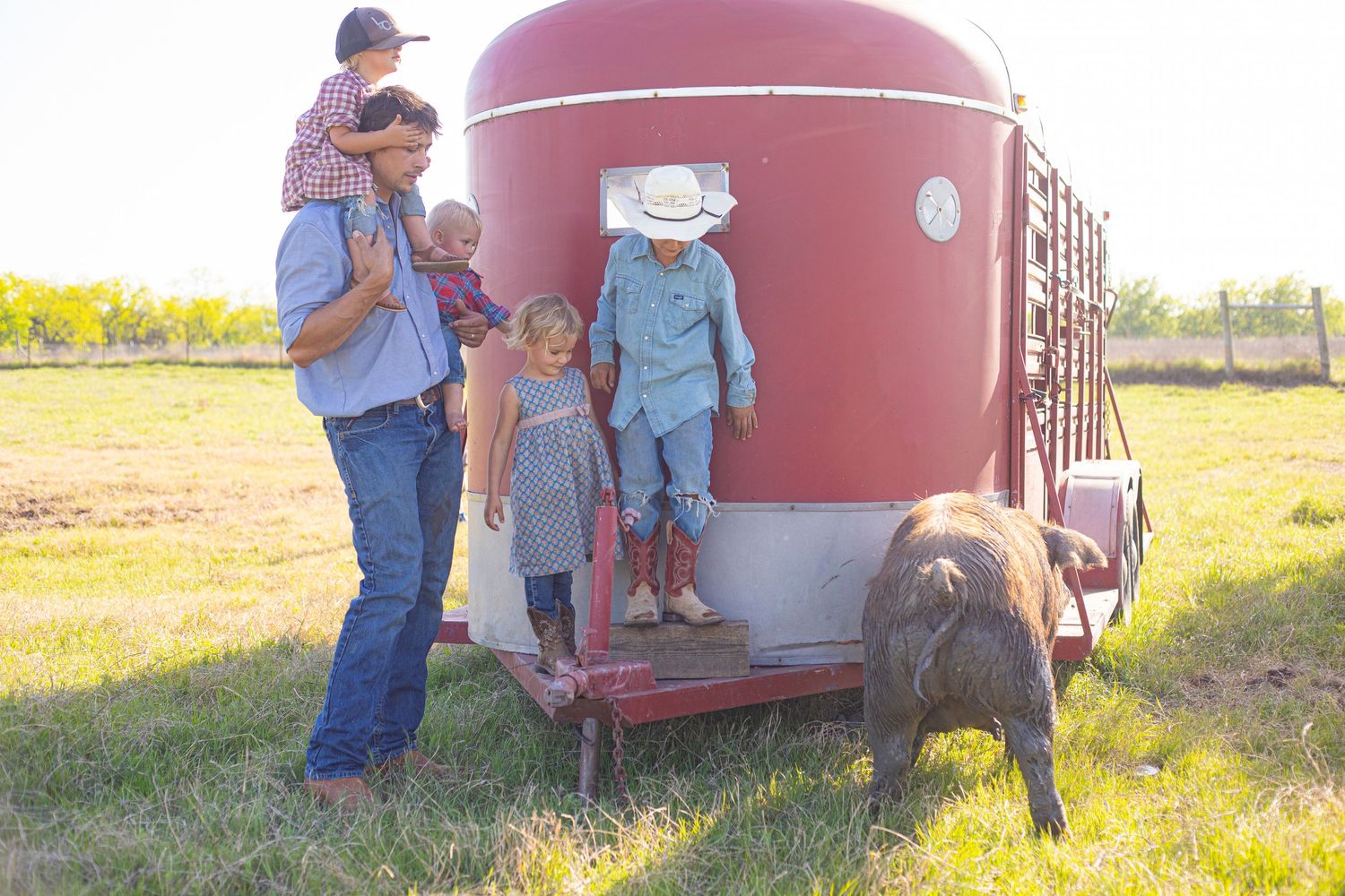 Family exploring around a large red grain bin on a farm.