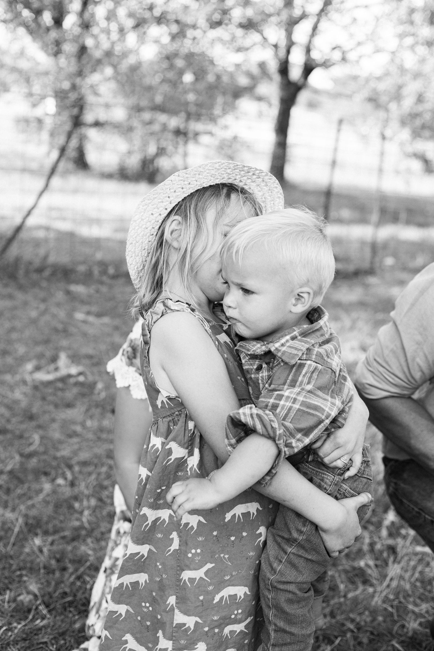 Sweet candid moment between two children sharing a hug outdoors.