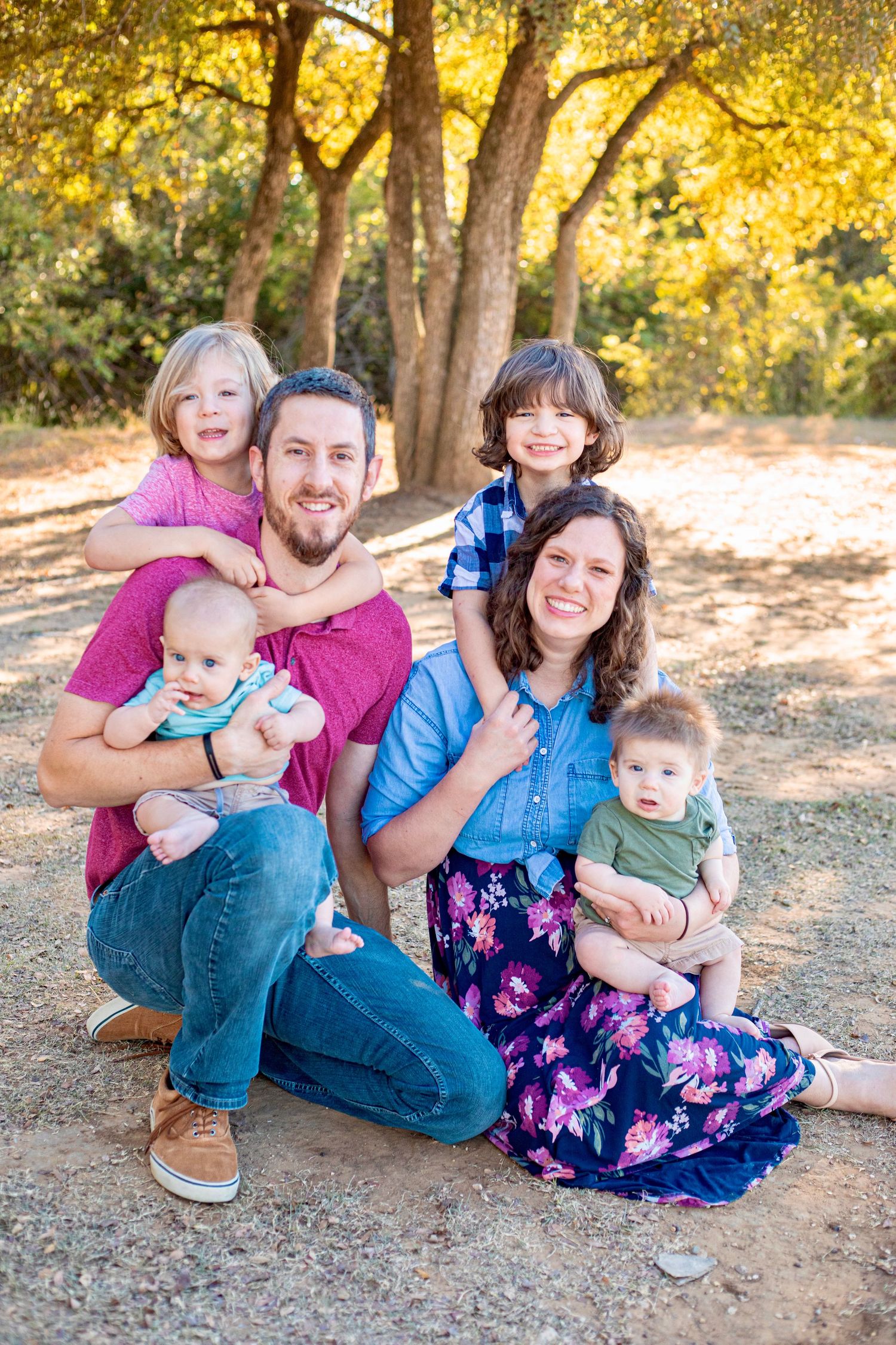 Family sitting together on ground during golden hour photo session with natural autumn lighting.