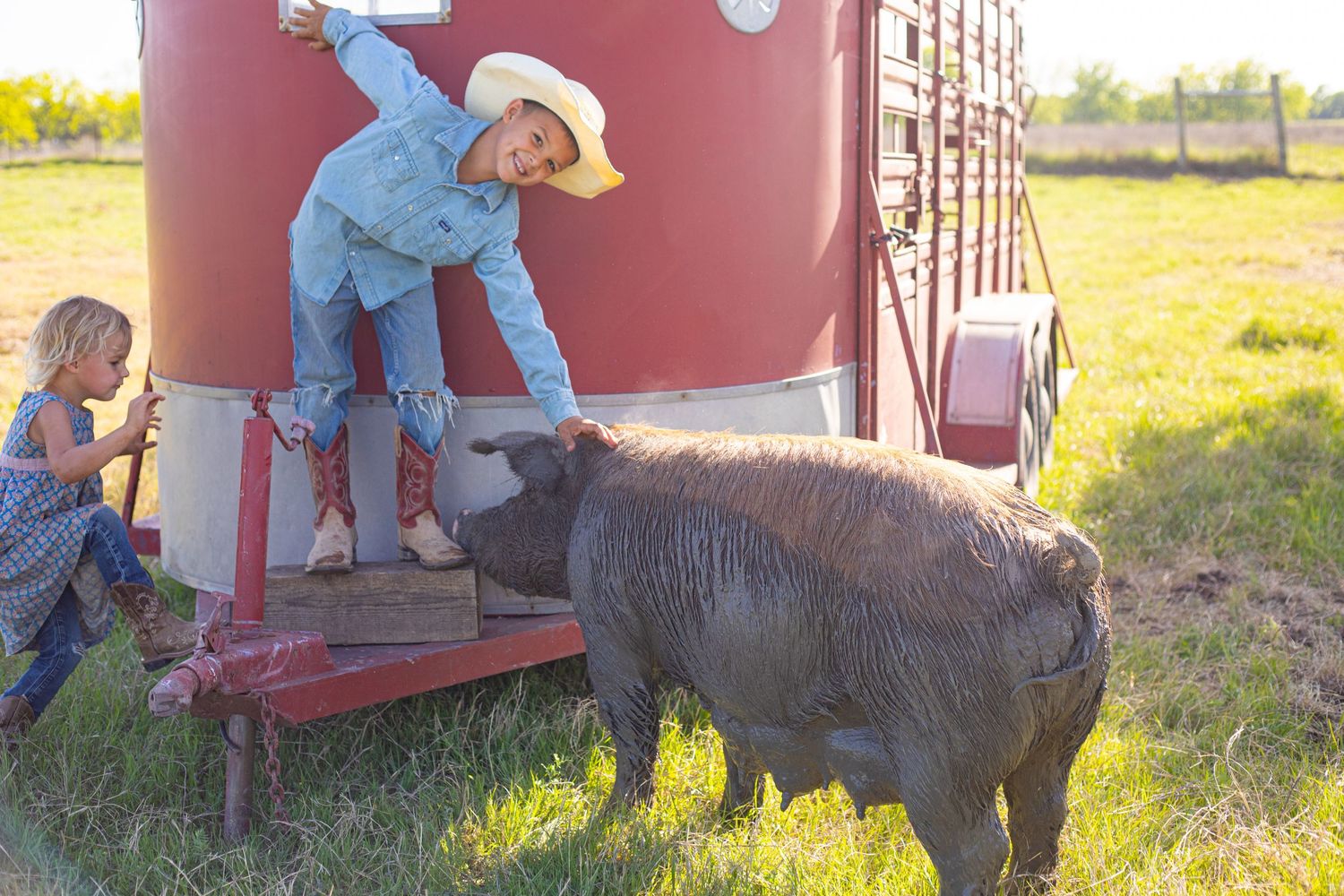 Children climbing on farm equipment next to a red grain bin.