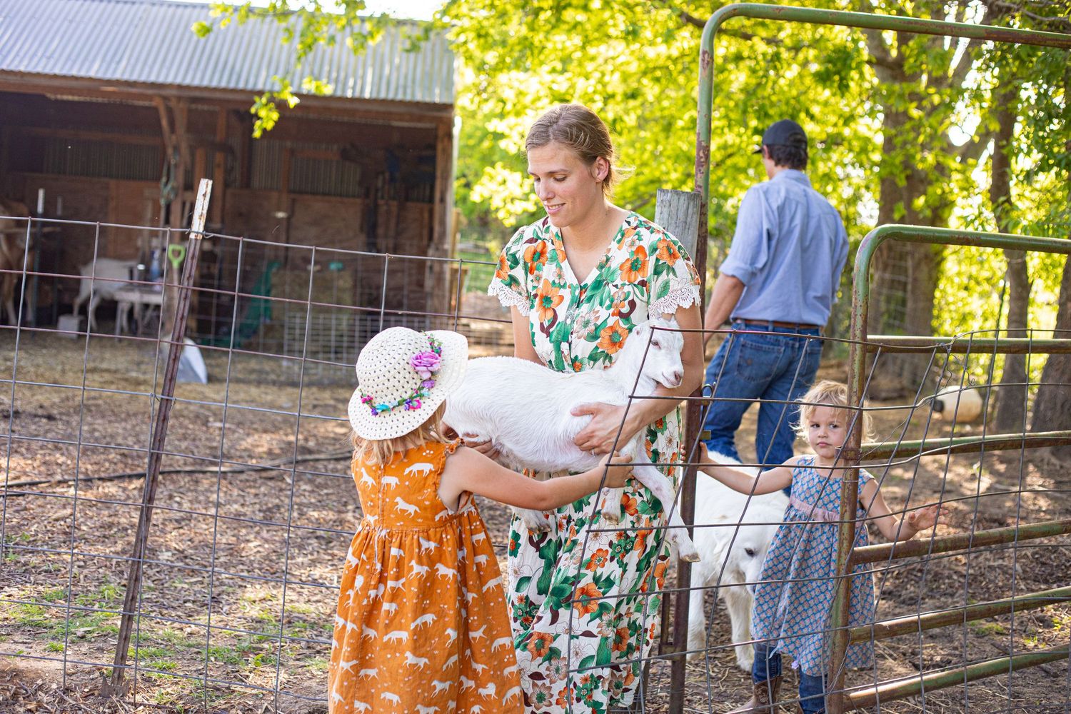 People gathered outdoors near a rustic wooden fence on a sunny day.
