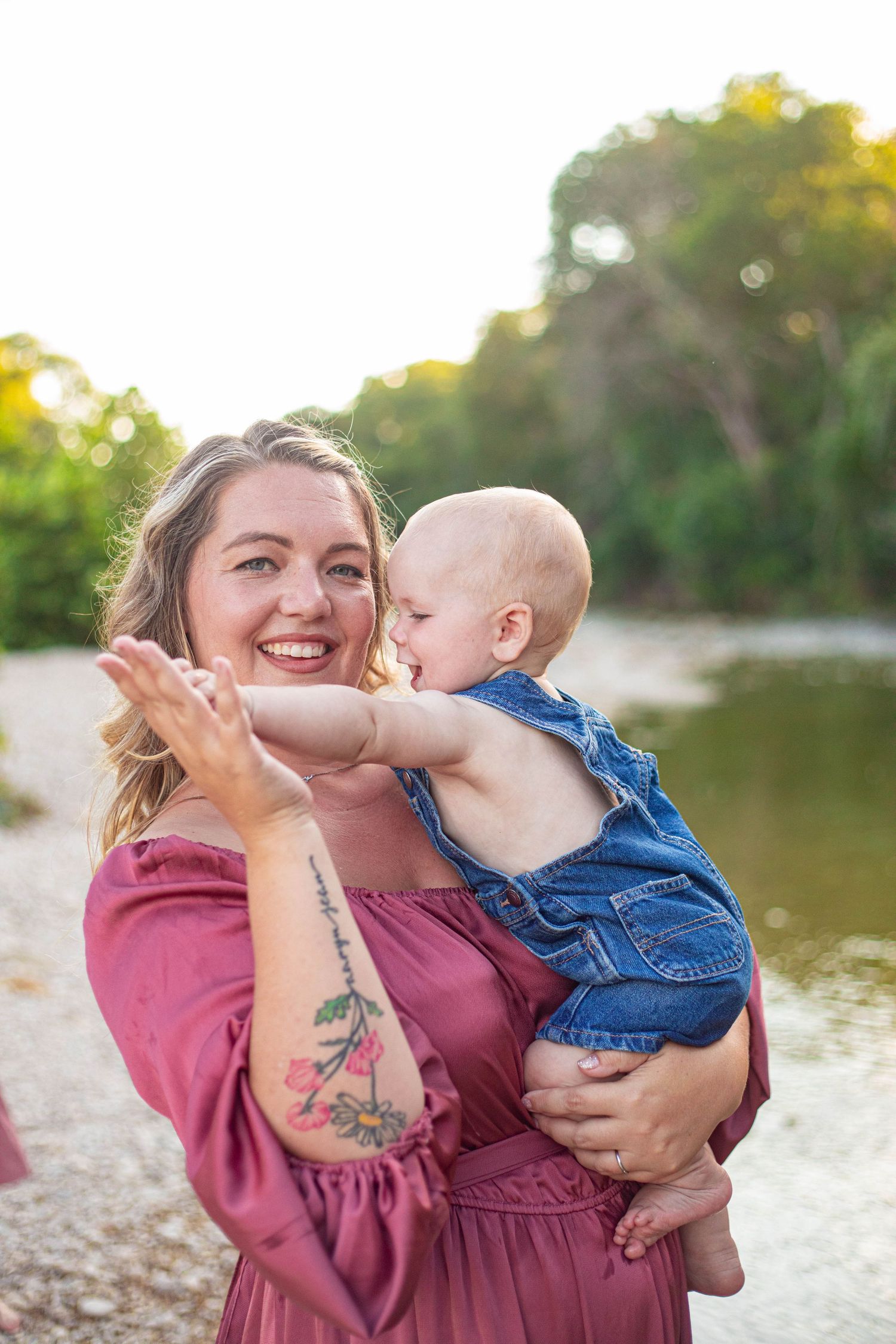 Tender moment shared between parent and child in matching pink and denim outfits by the river.