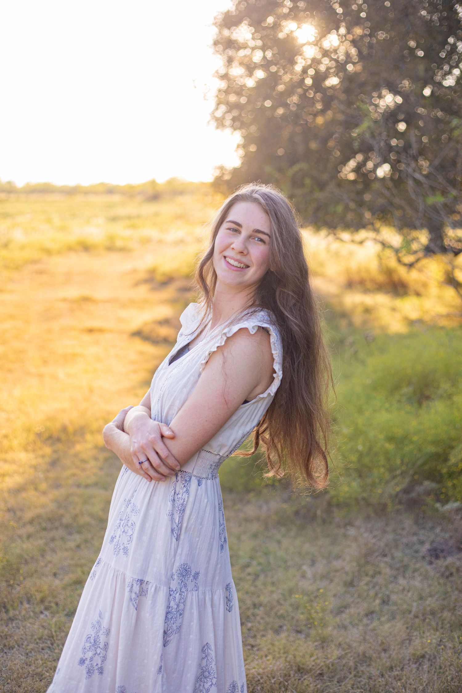 Playful poses in white summer dress during golden sunset photoshoot.