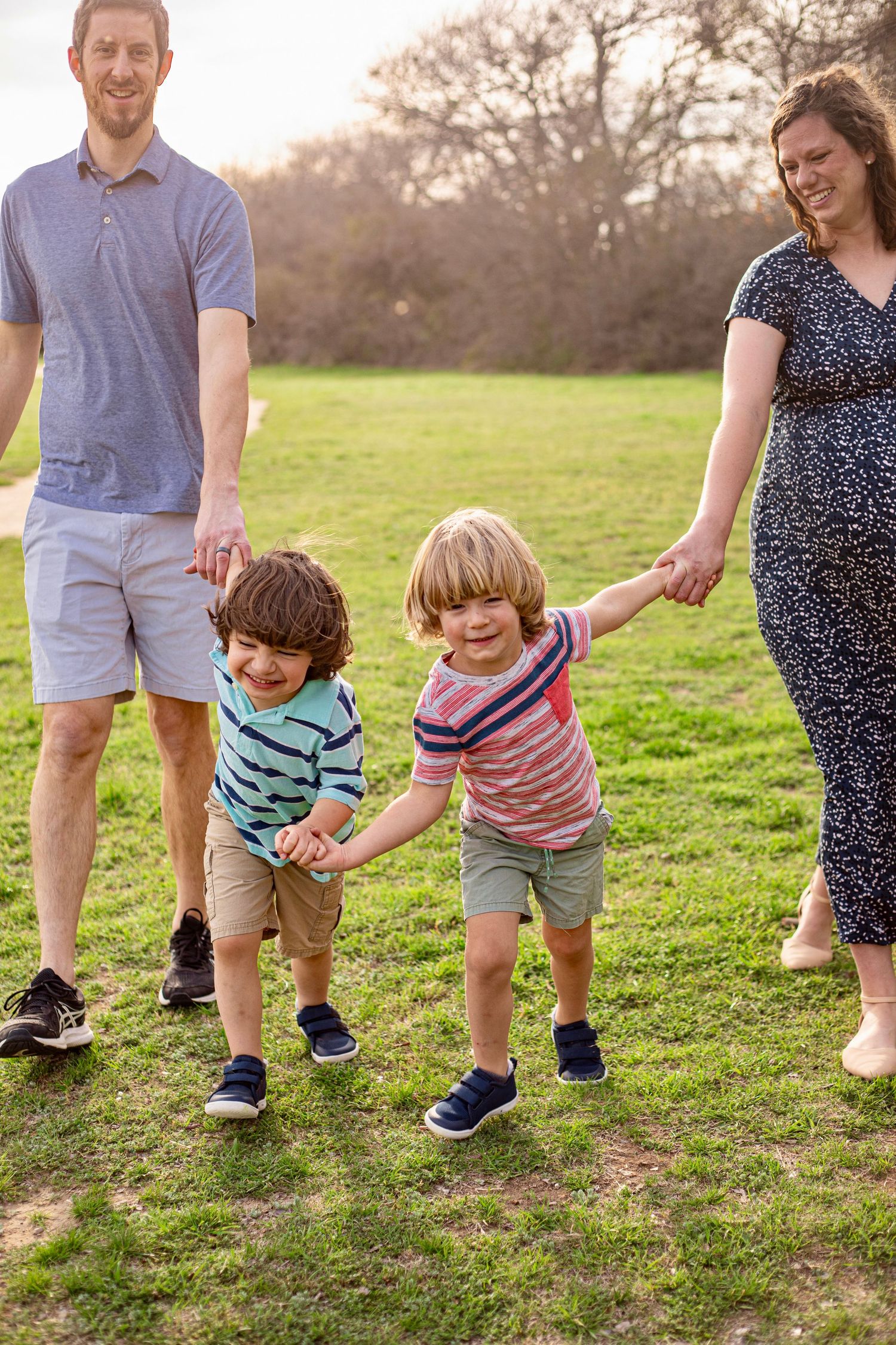 Family playing together on green grass during golden hour.