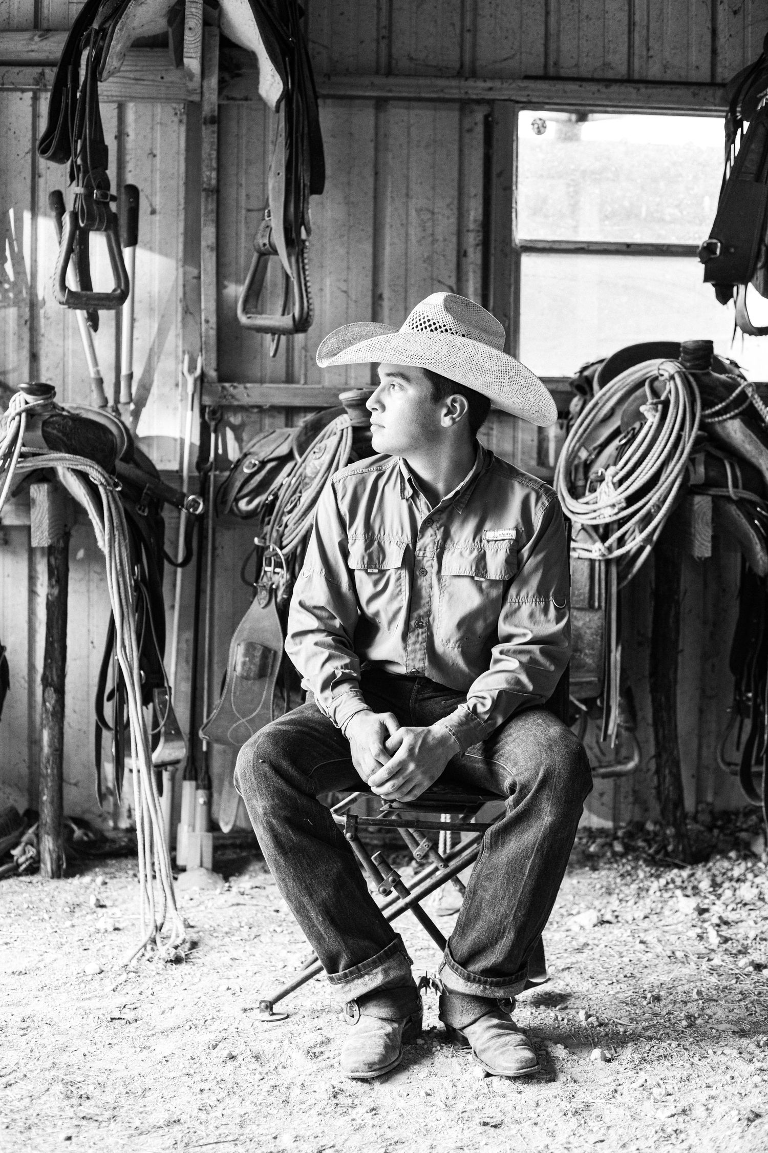 Black and white photo of someone working with equipment in a rustic barn setting.