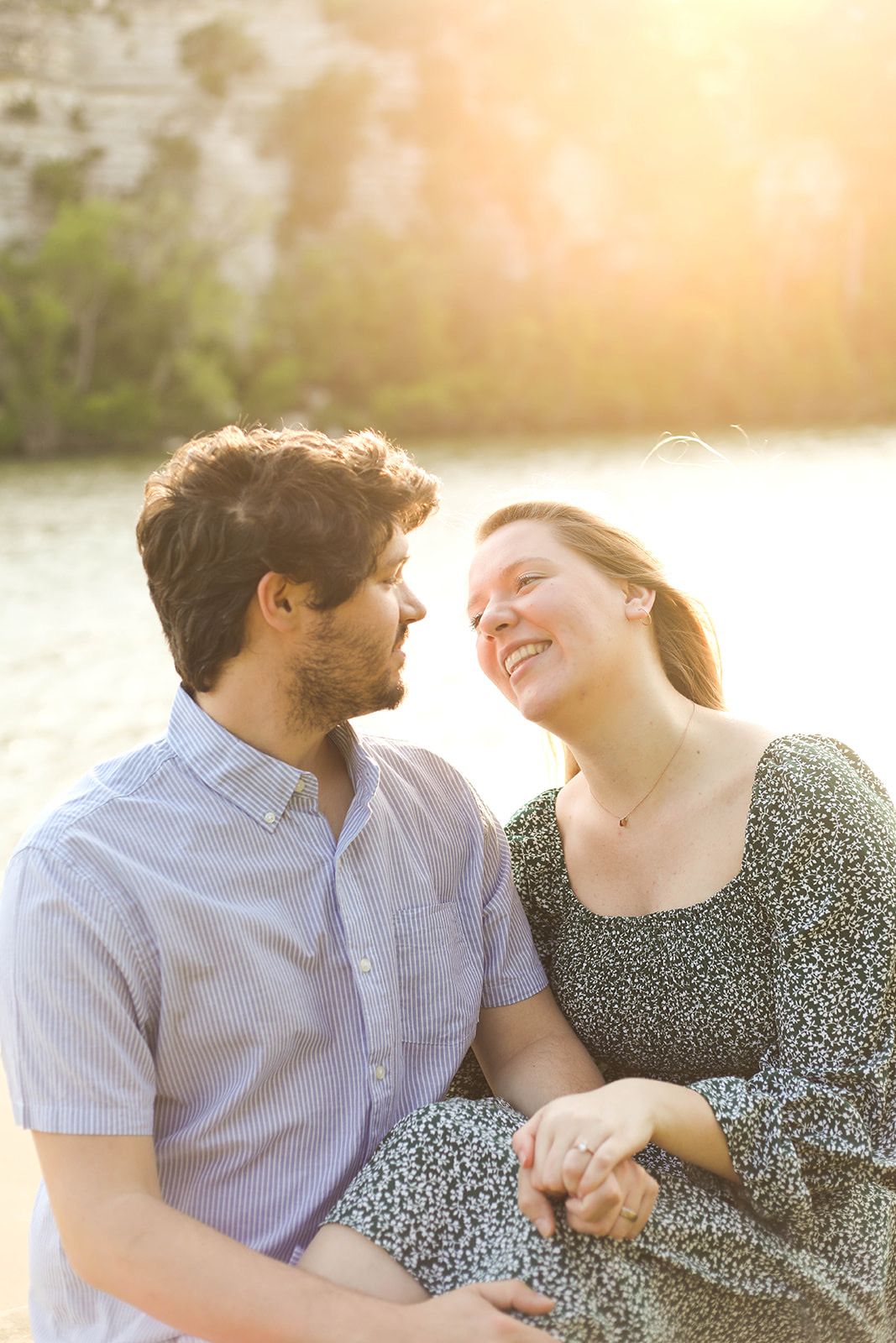 Couple enjoying intimate moment in sunlit outdoor setting.