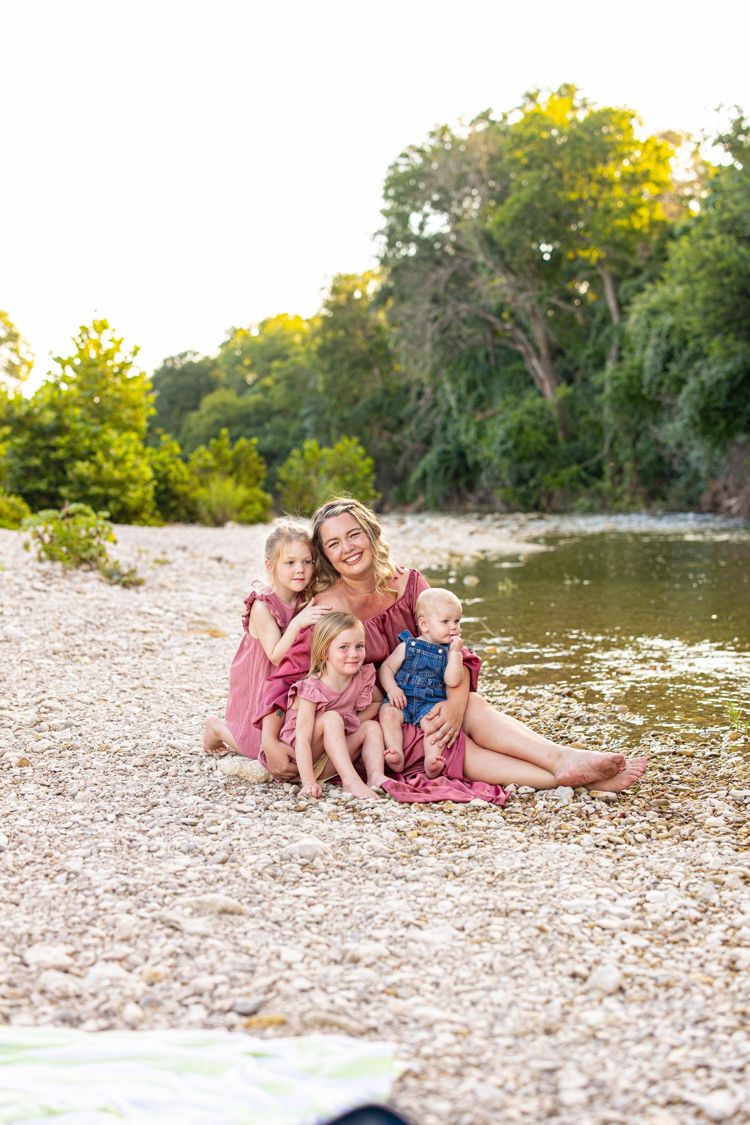 Natural light photography session capturing tender family moments by the water.