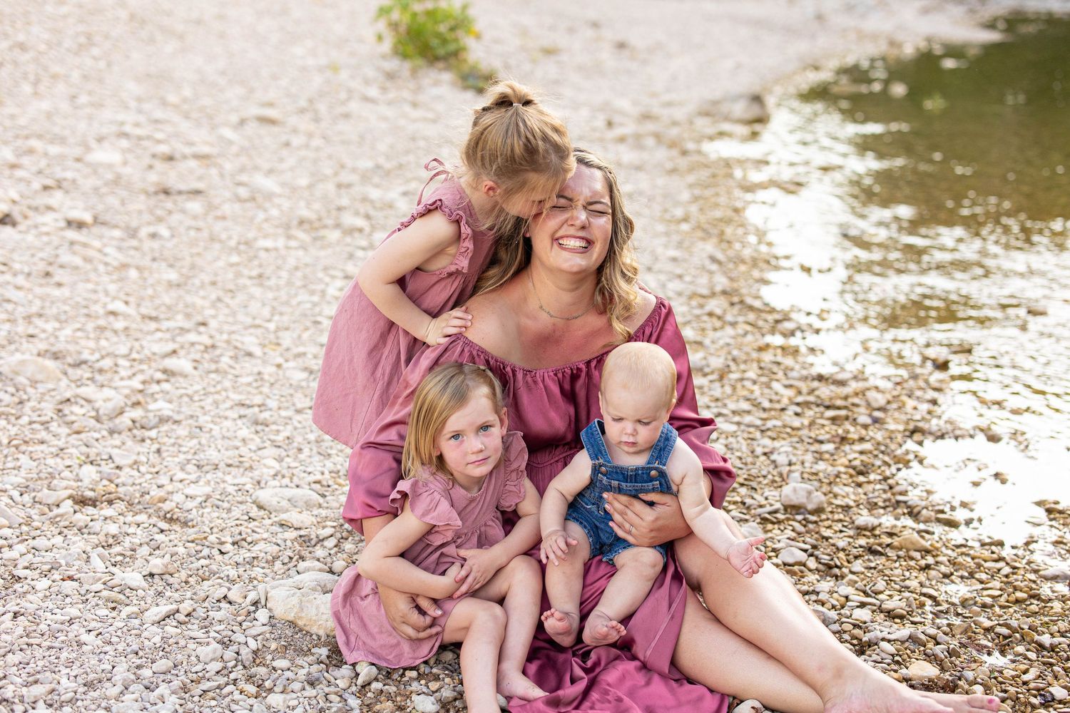 Loving family embracing and laughing together on rocky riverside terrain.