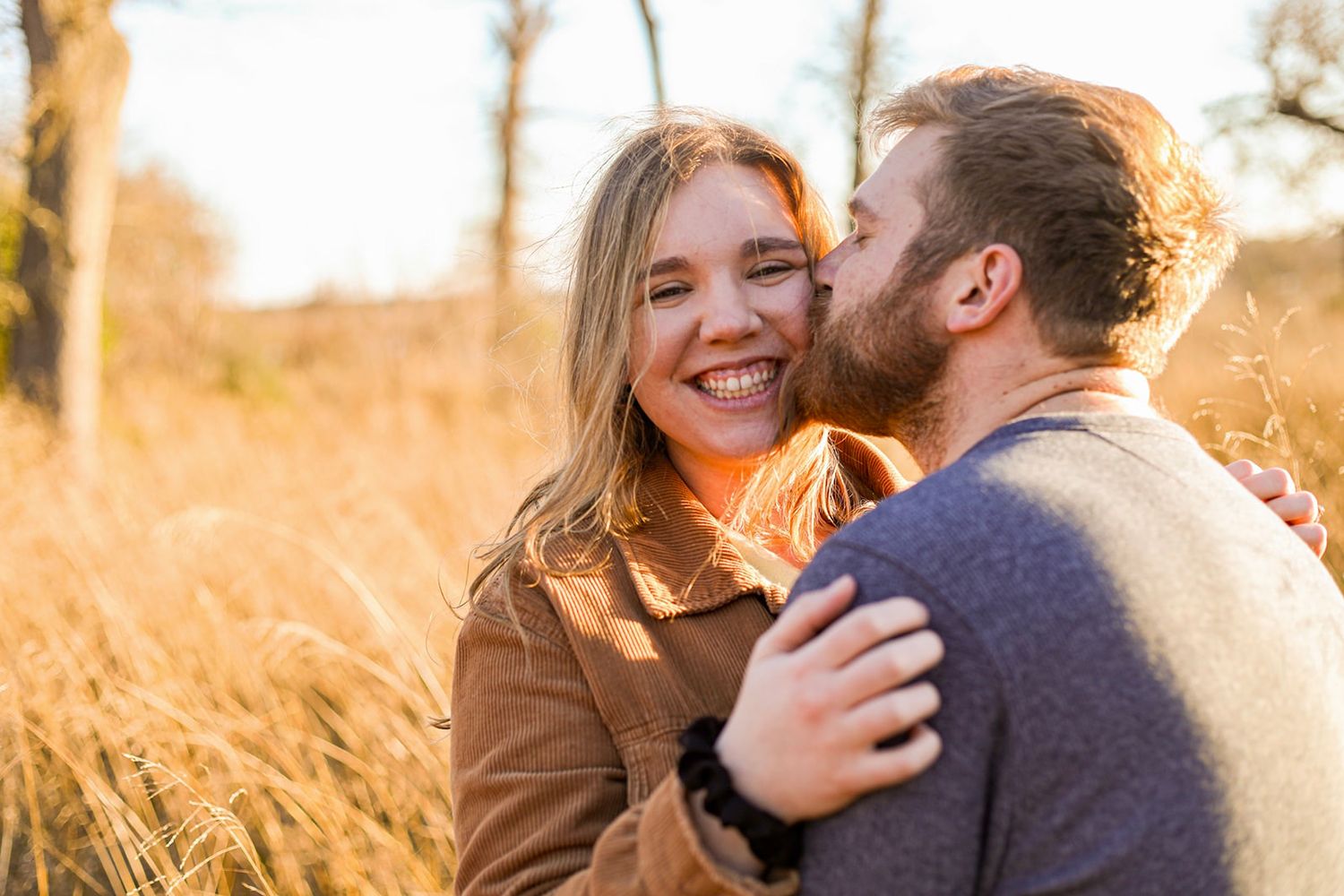 Romantic couple embraces in a golden field during sunset photoshoot.