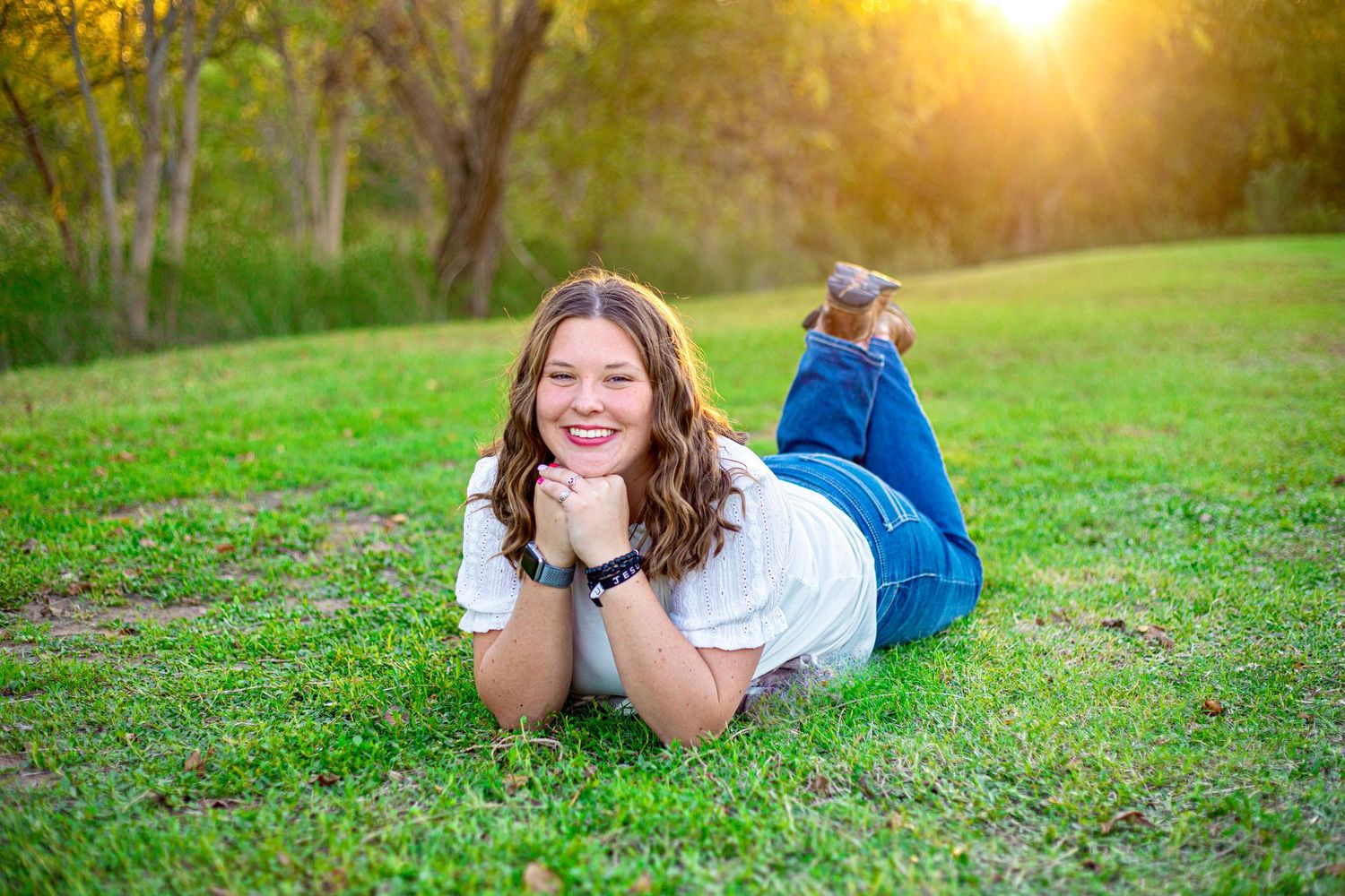 A casual outdoor portrait session in a grassy field during golden hour sunset.