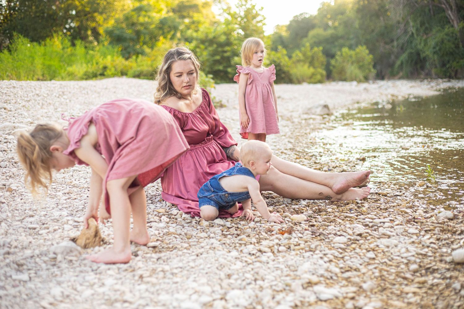Candid moments on a rocky riverbank in pink summer attire.